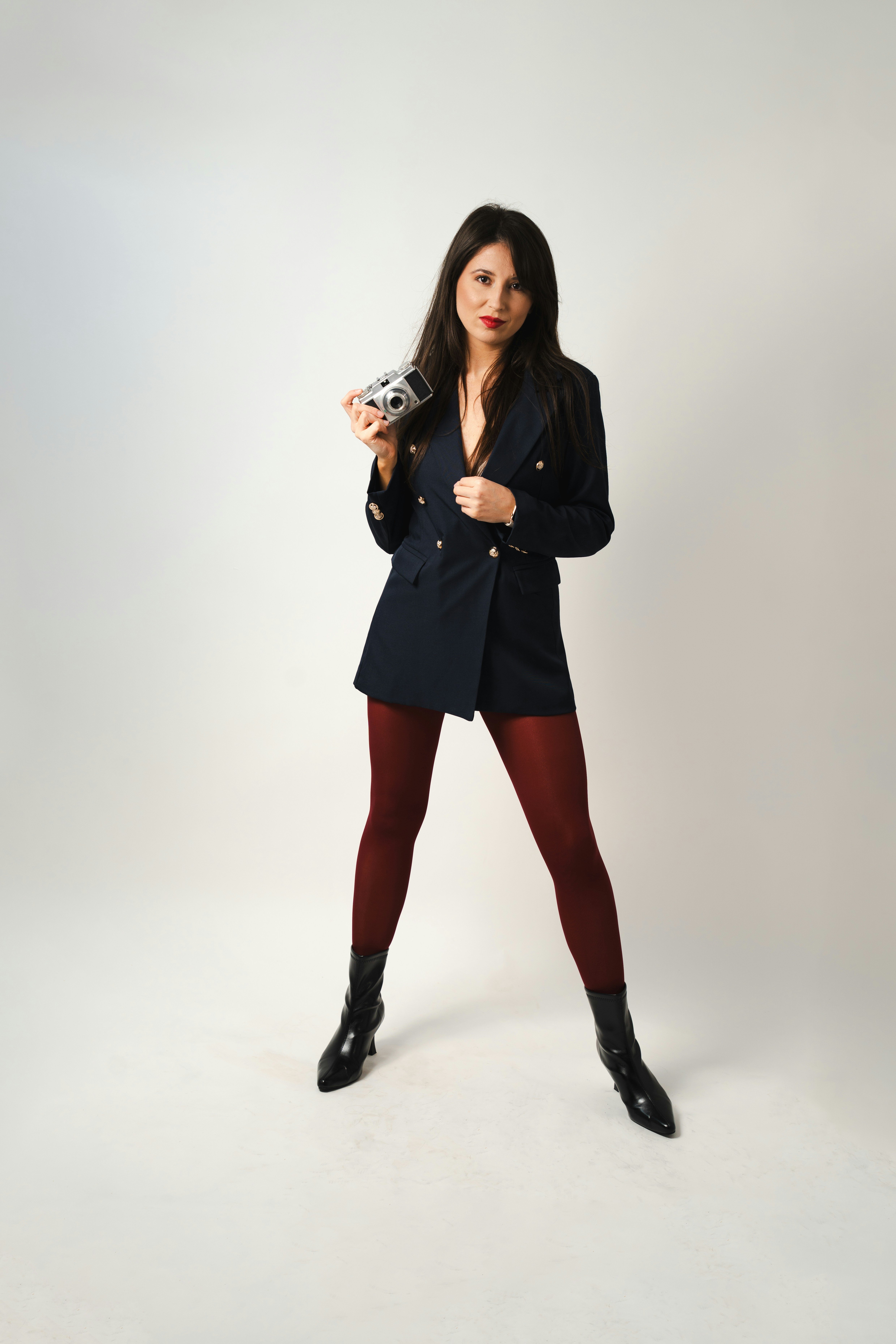 Mujer con americana sosteniendo una cámara vintage