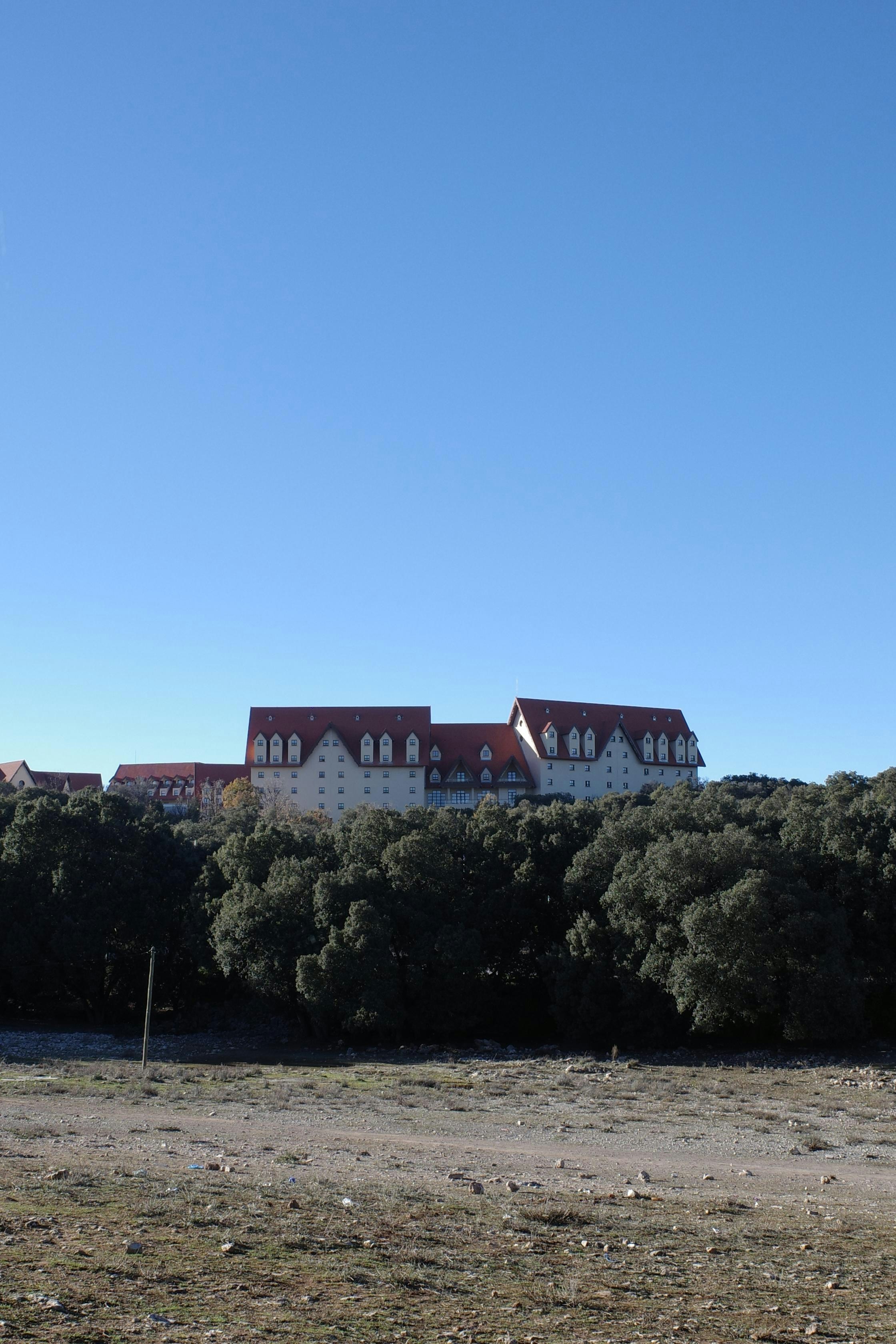 Large building with red roofs behind trees