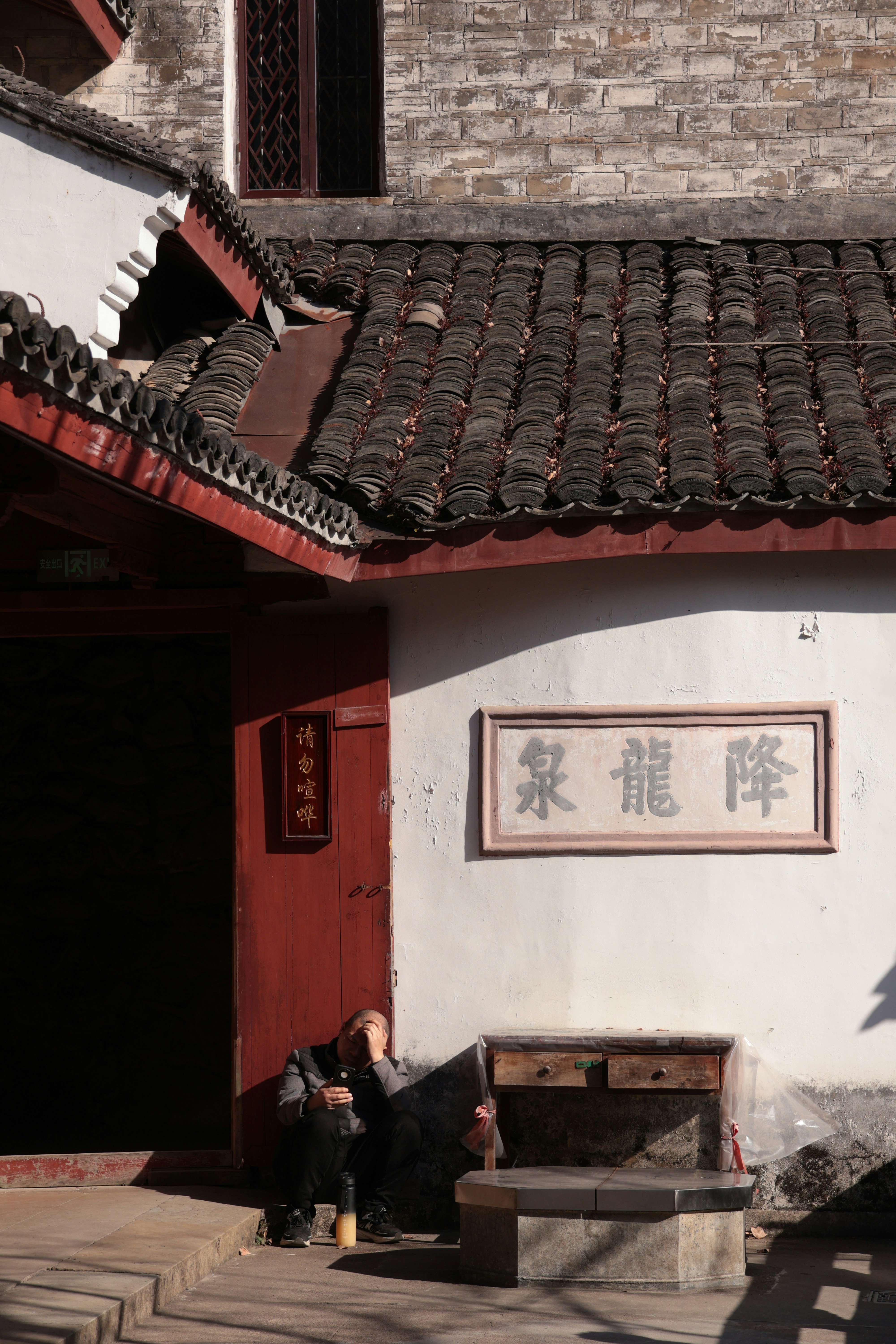 Man sitting by traditional chinese building entrance