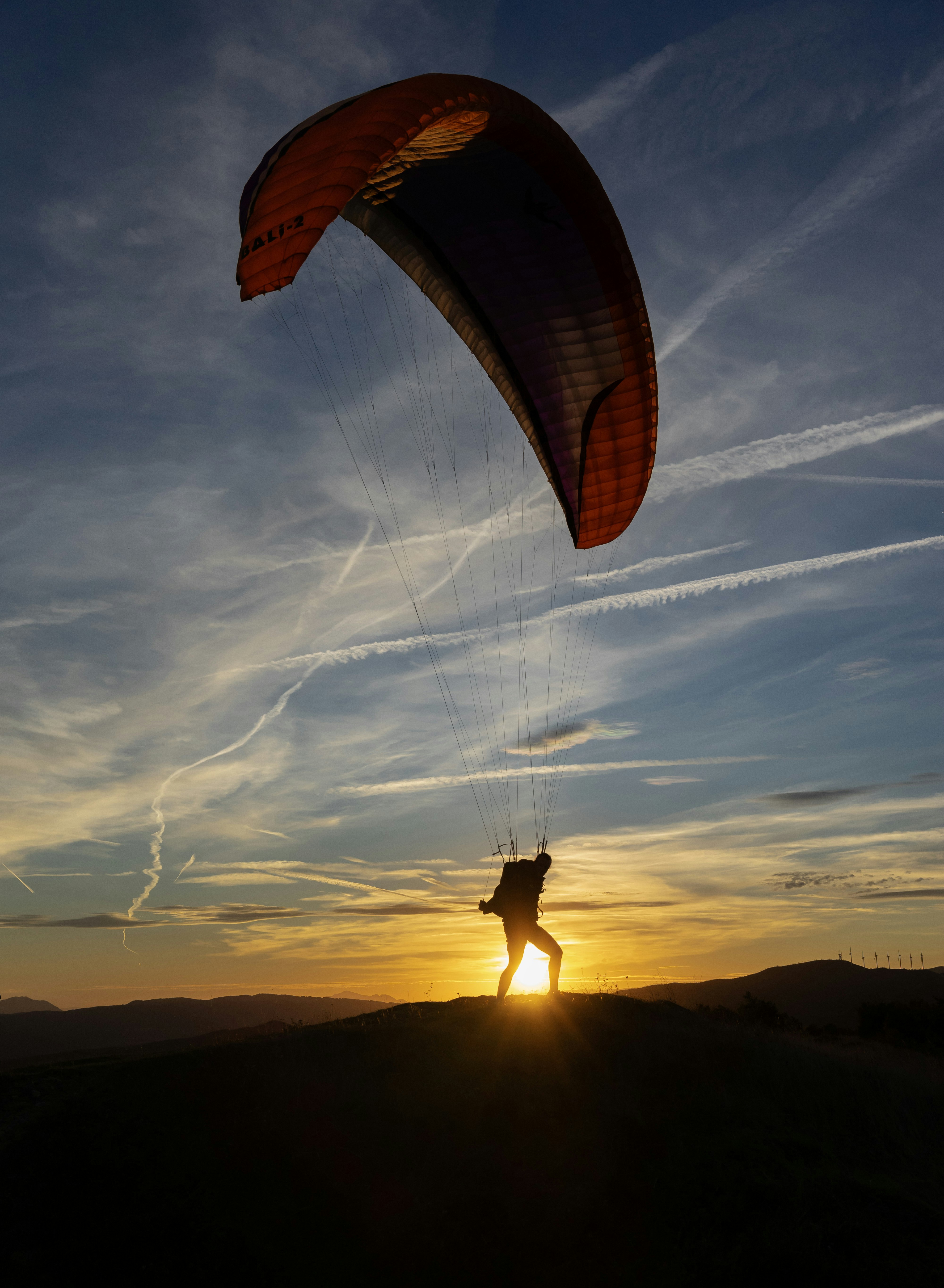 Paraglider silhouette against a vibrant sunset sky