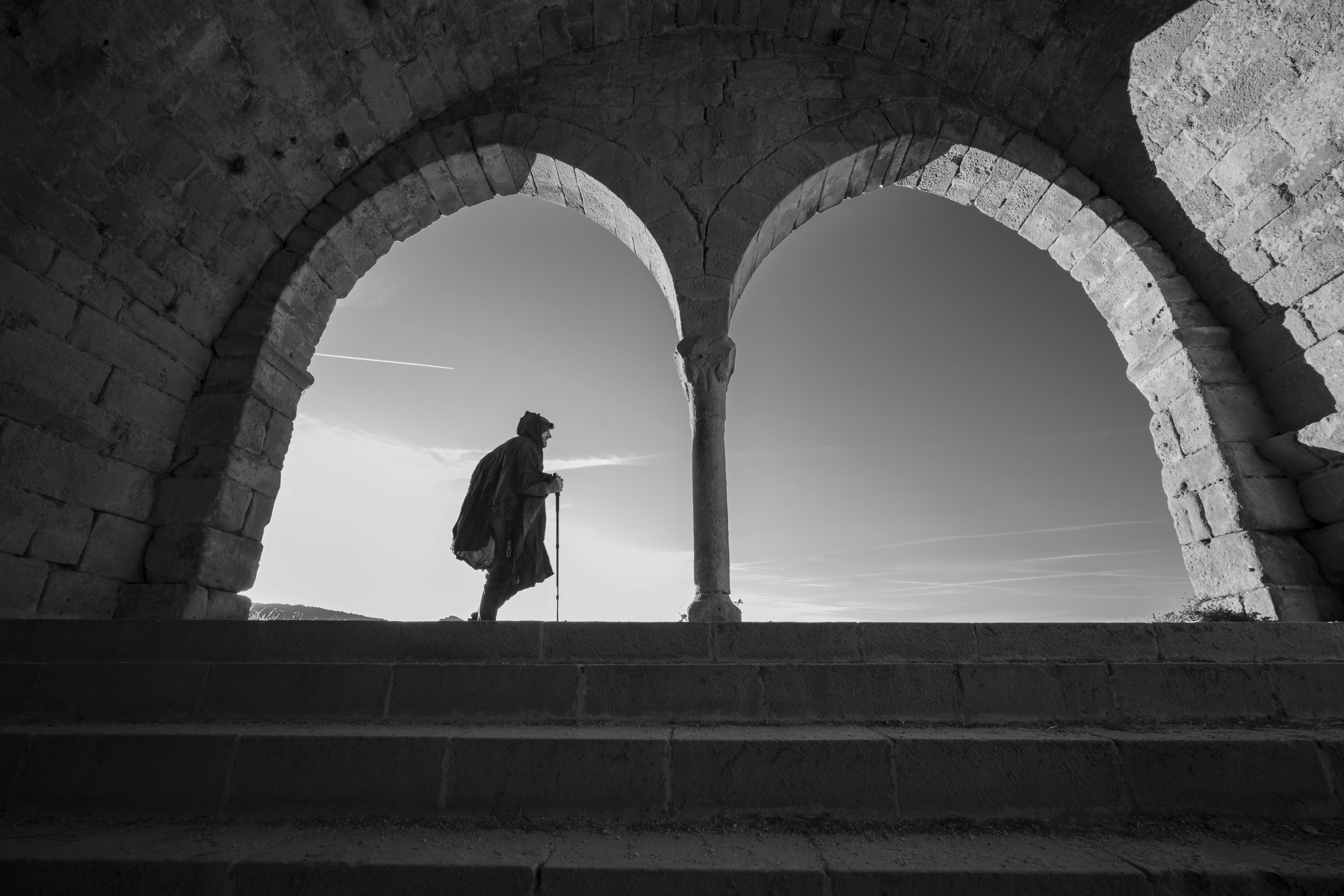 Man walking through ancient stone arches