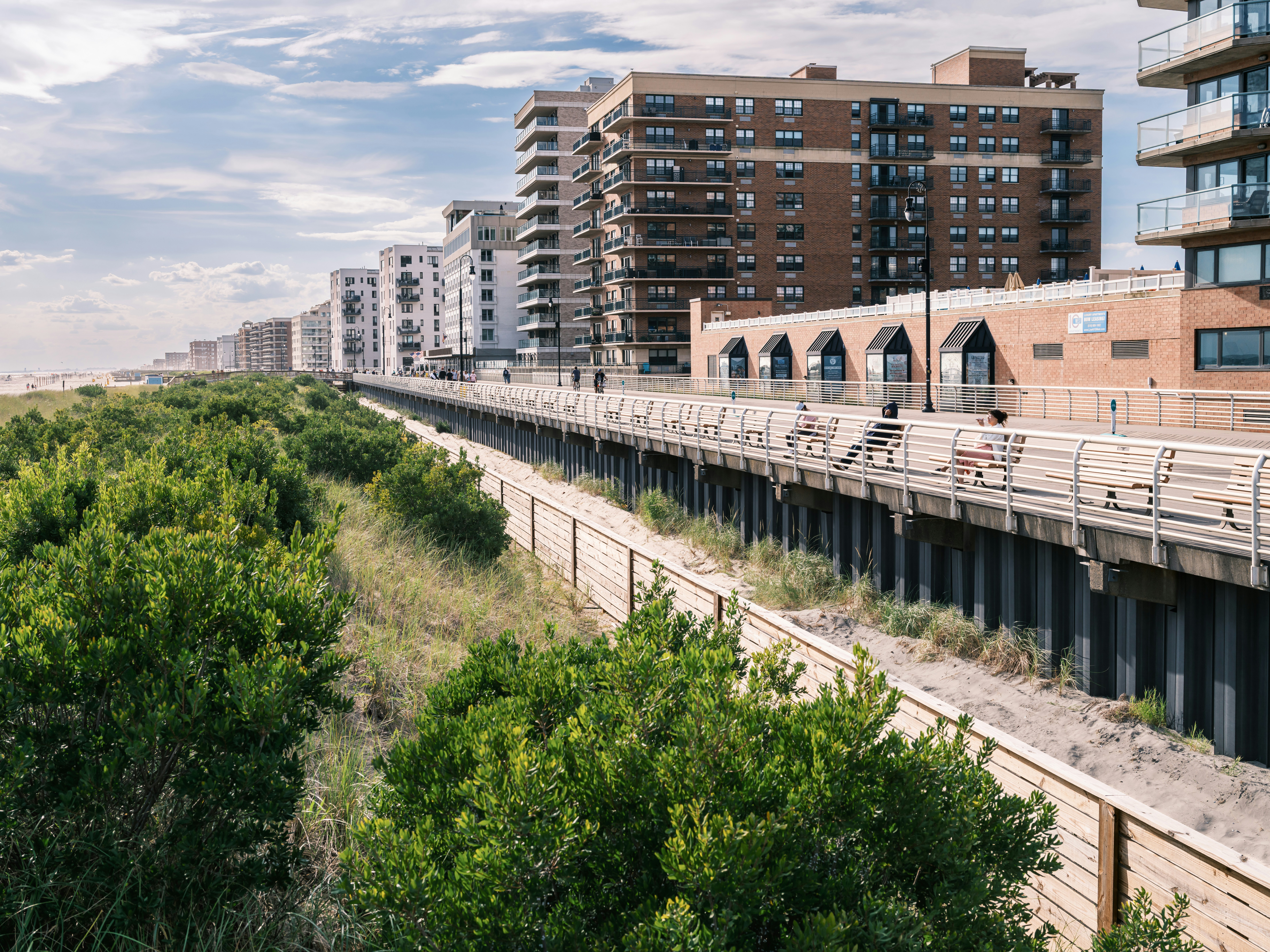 Apartment buildings line a boardwalk with lush greenery.
