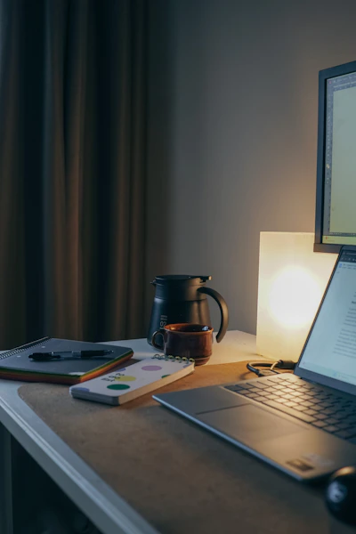 Laptop, notebook, and coffee on a desk.