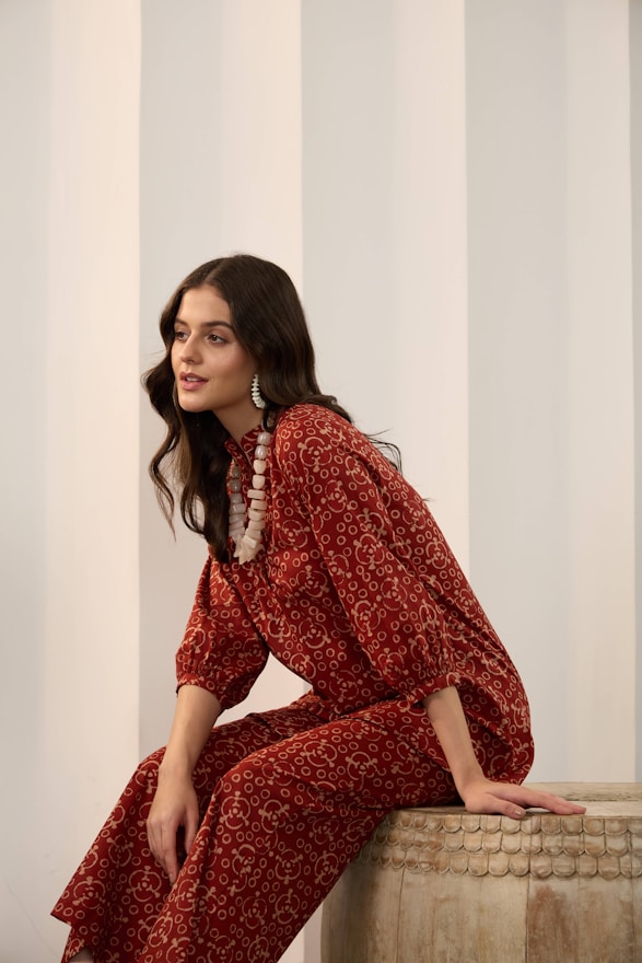 A woman in a patterned red outfit and statement necklace.