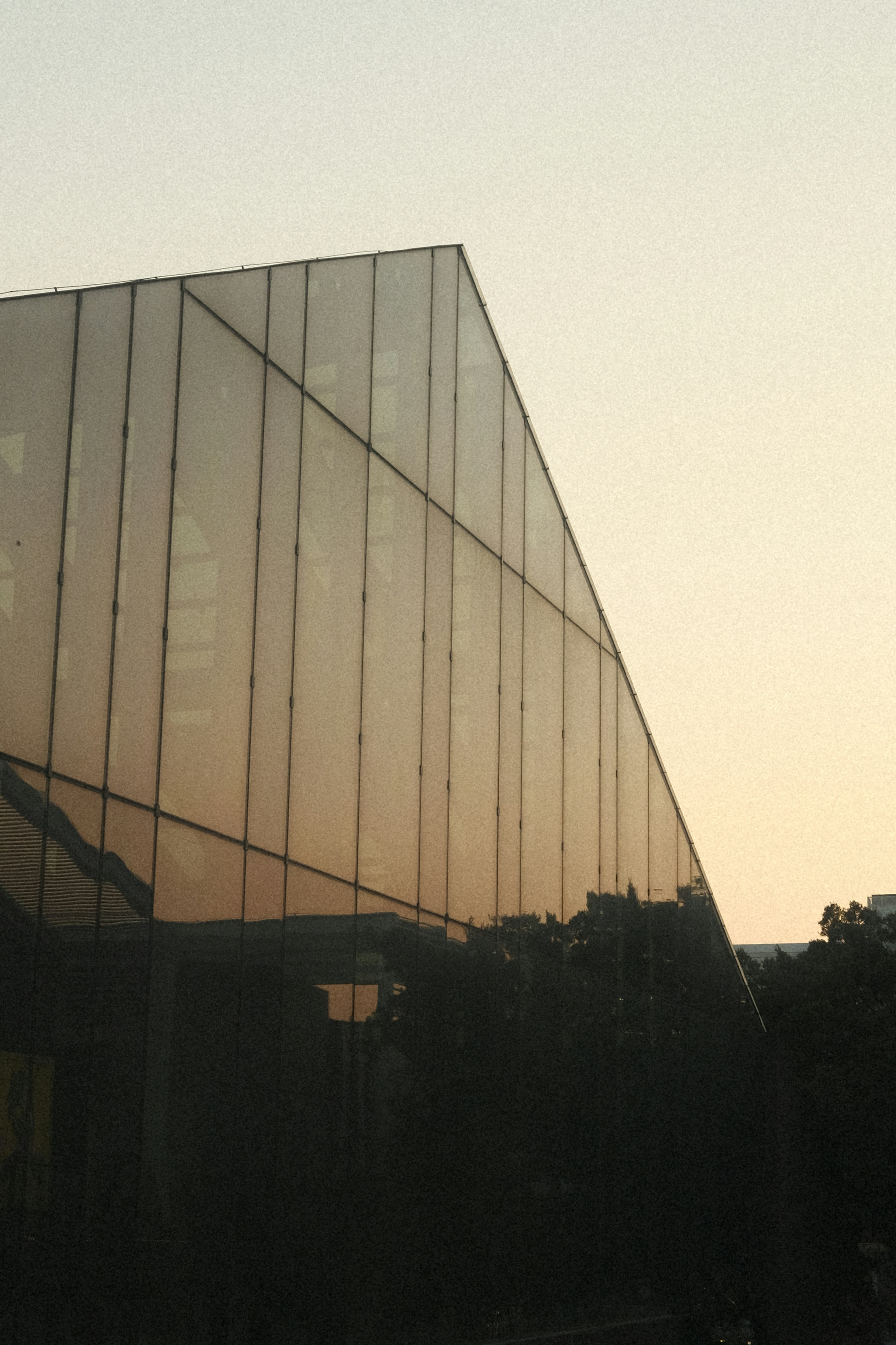 Modern glass building reflecting the sky at sunset