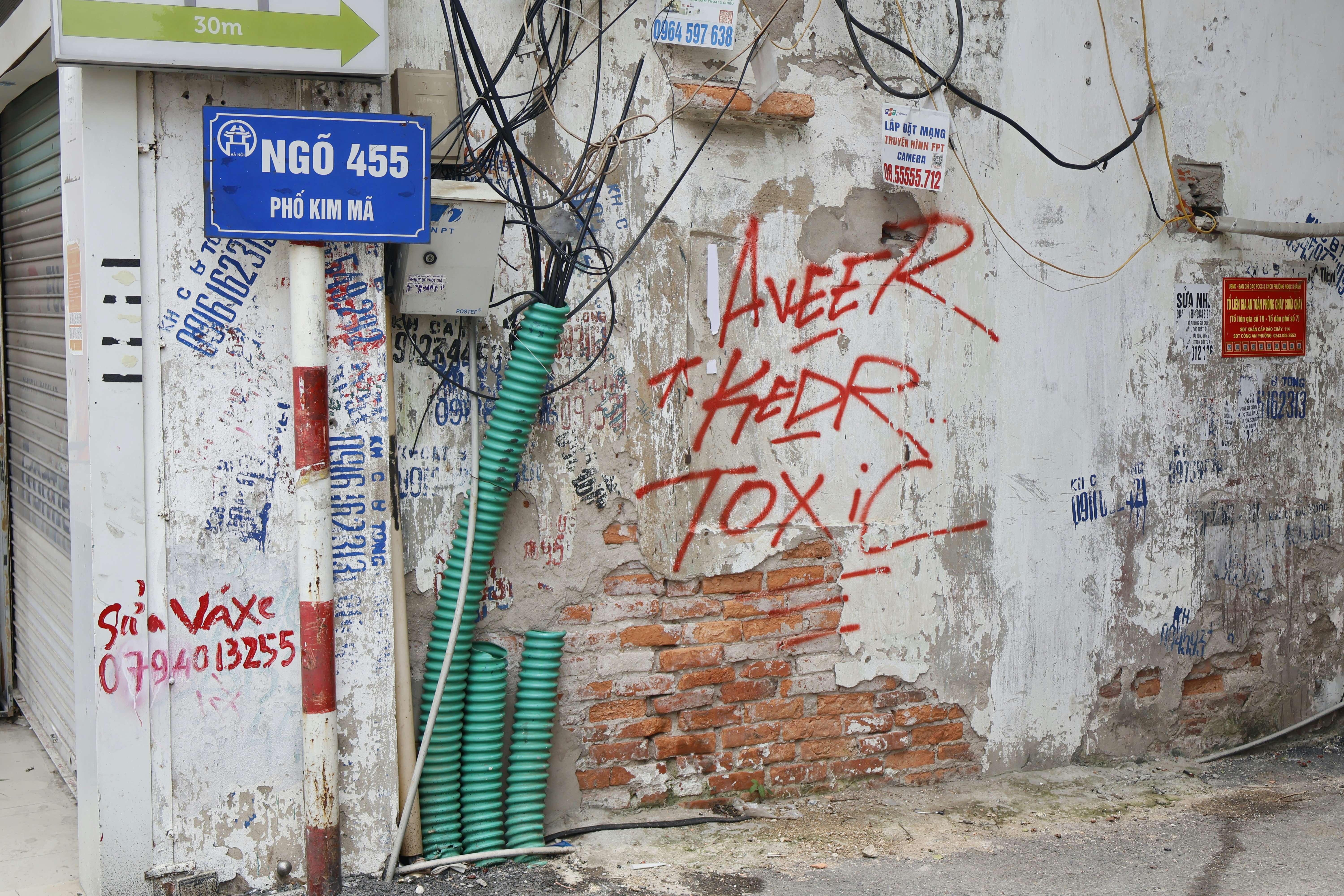 Pichação em uma parede de tijolos desgastada com placa de rua.