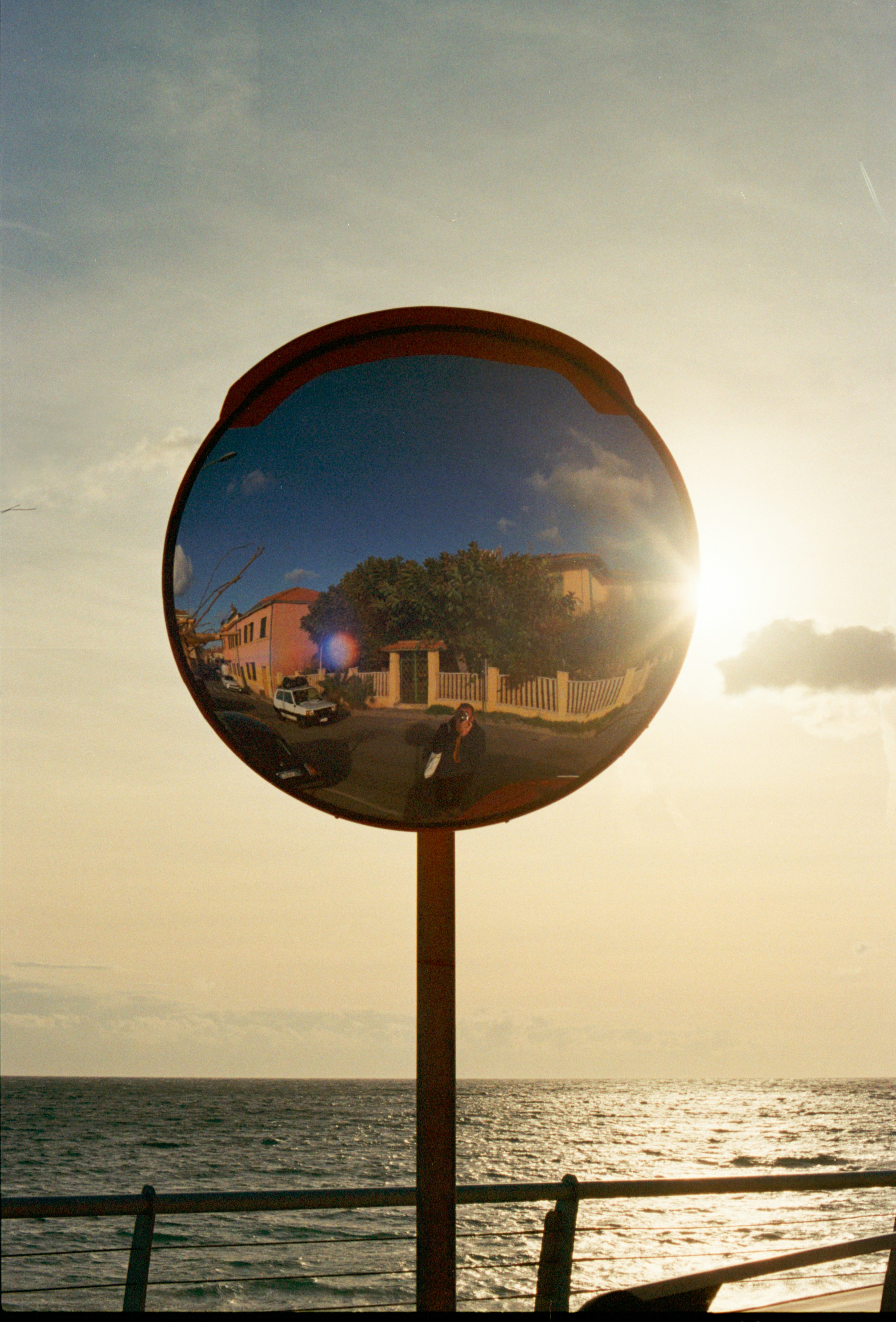 Konvexer Spiegel, der eine Straßenszene bei Sonnenuntergang reflektiert.