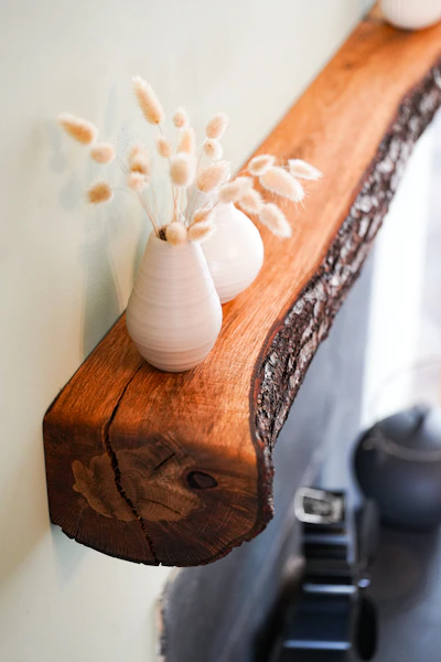 Wooden shelf with decorative vases and dried flowers.