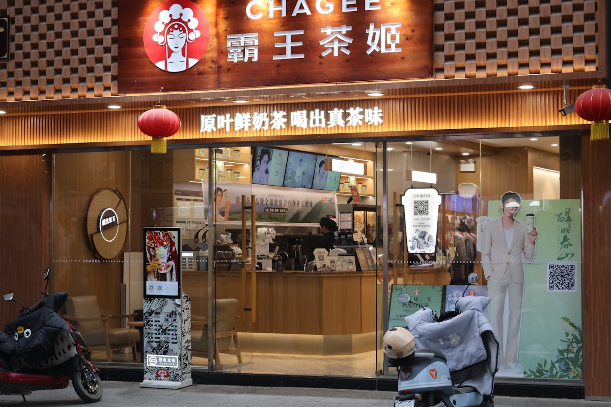 A Chagee bubble tea storefront in China with red lanterns and a sign reading 'real tea leaves, fresh milk tea'