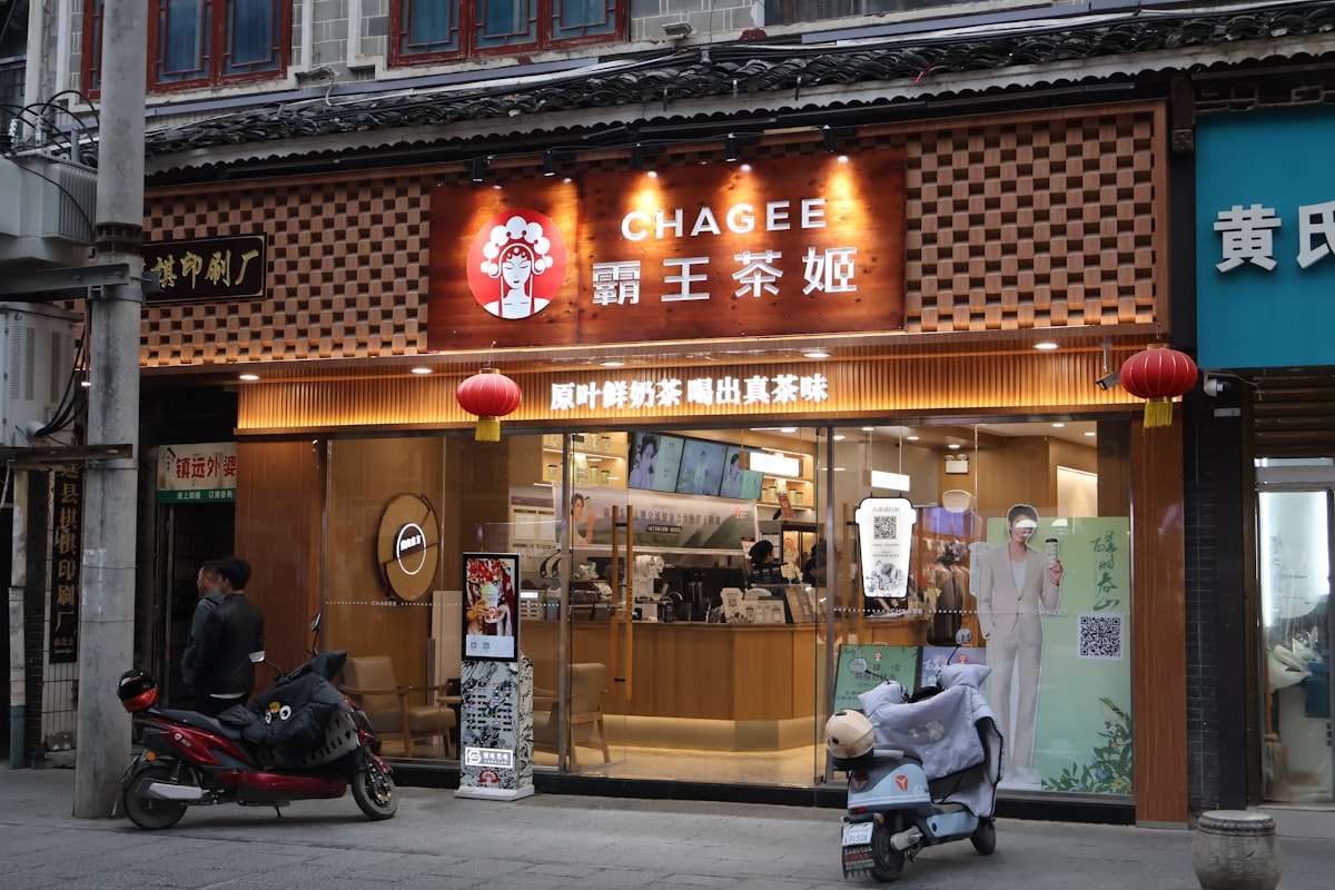 A Chagee bubble tea shop storefront in China with motorcycles parked outside, representing the country's competitive tea franchise market