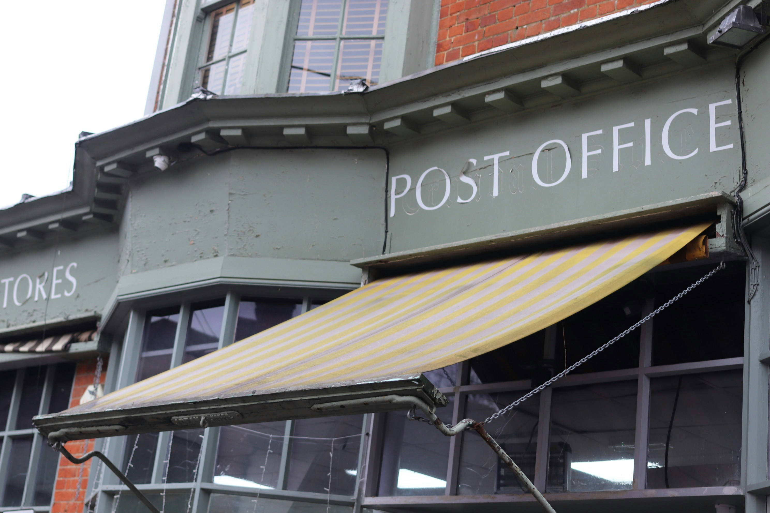 Exterior de un edificio de correos con toldo.