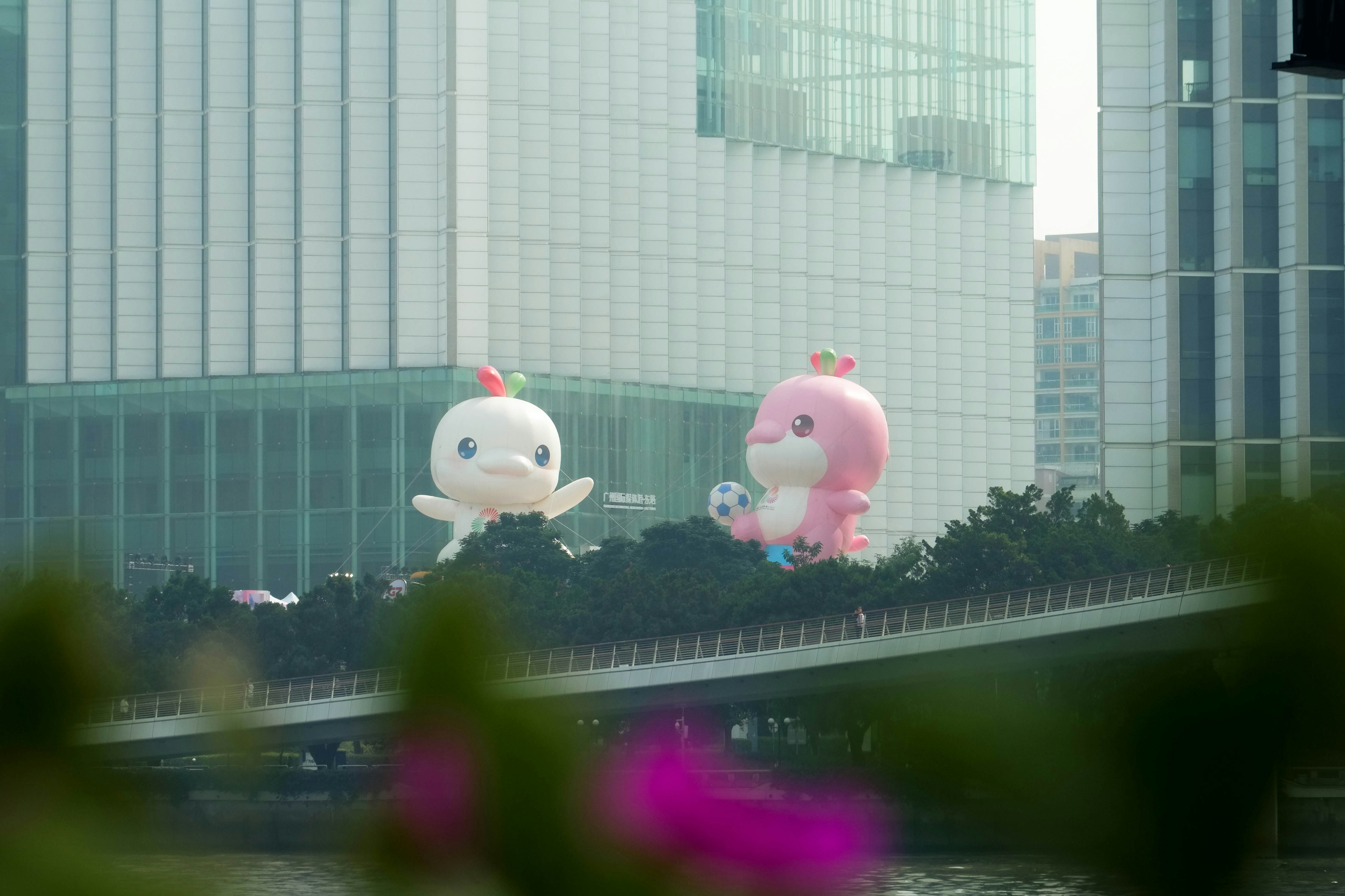 Two inflatable cartoon characters float above trees.