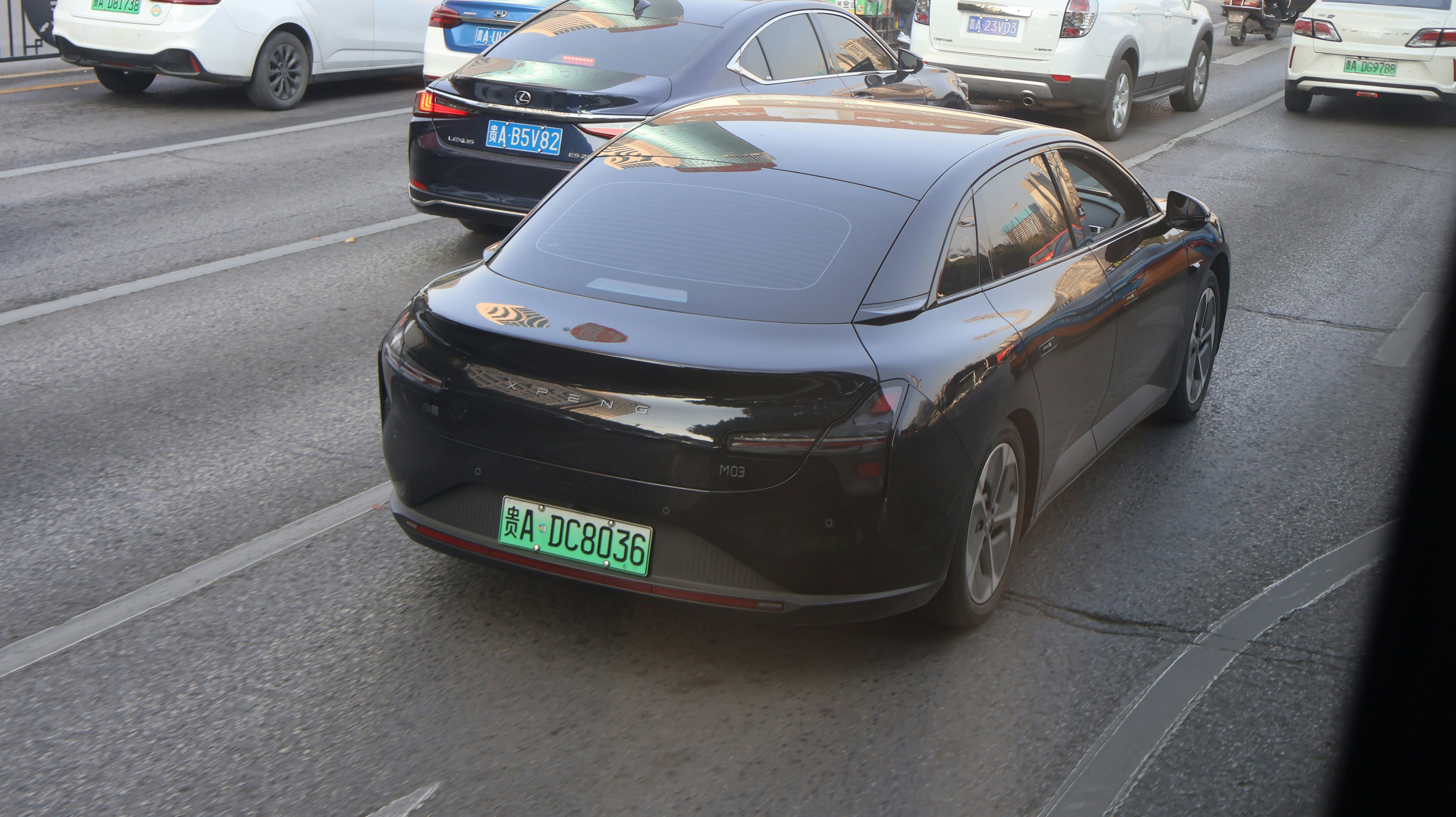 A black car drives on a busy road.