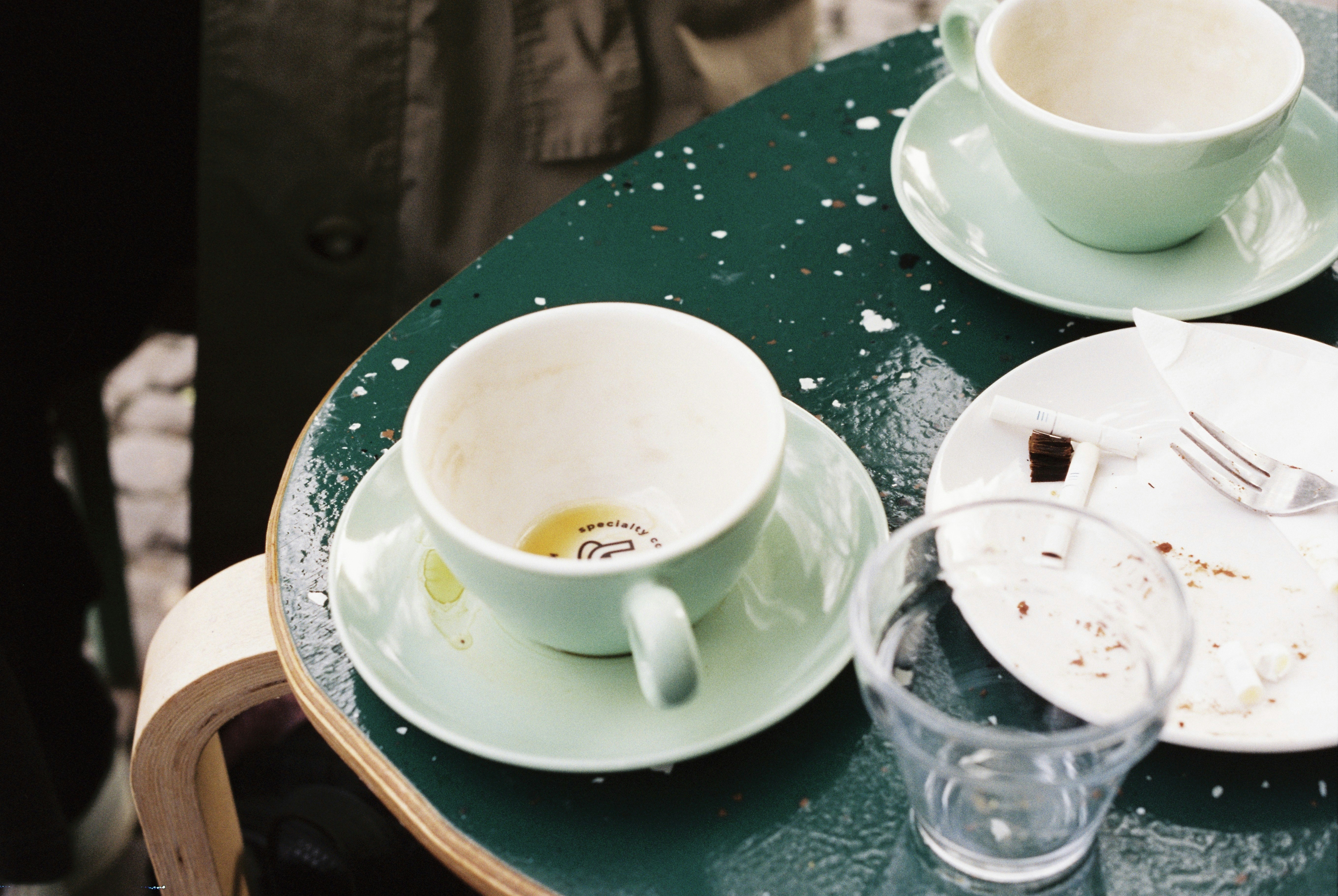 Two empty teacups and a plate on a green table
