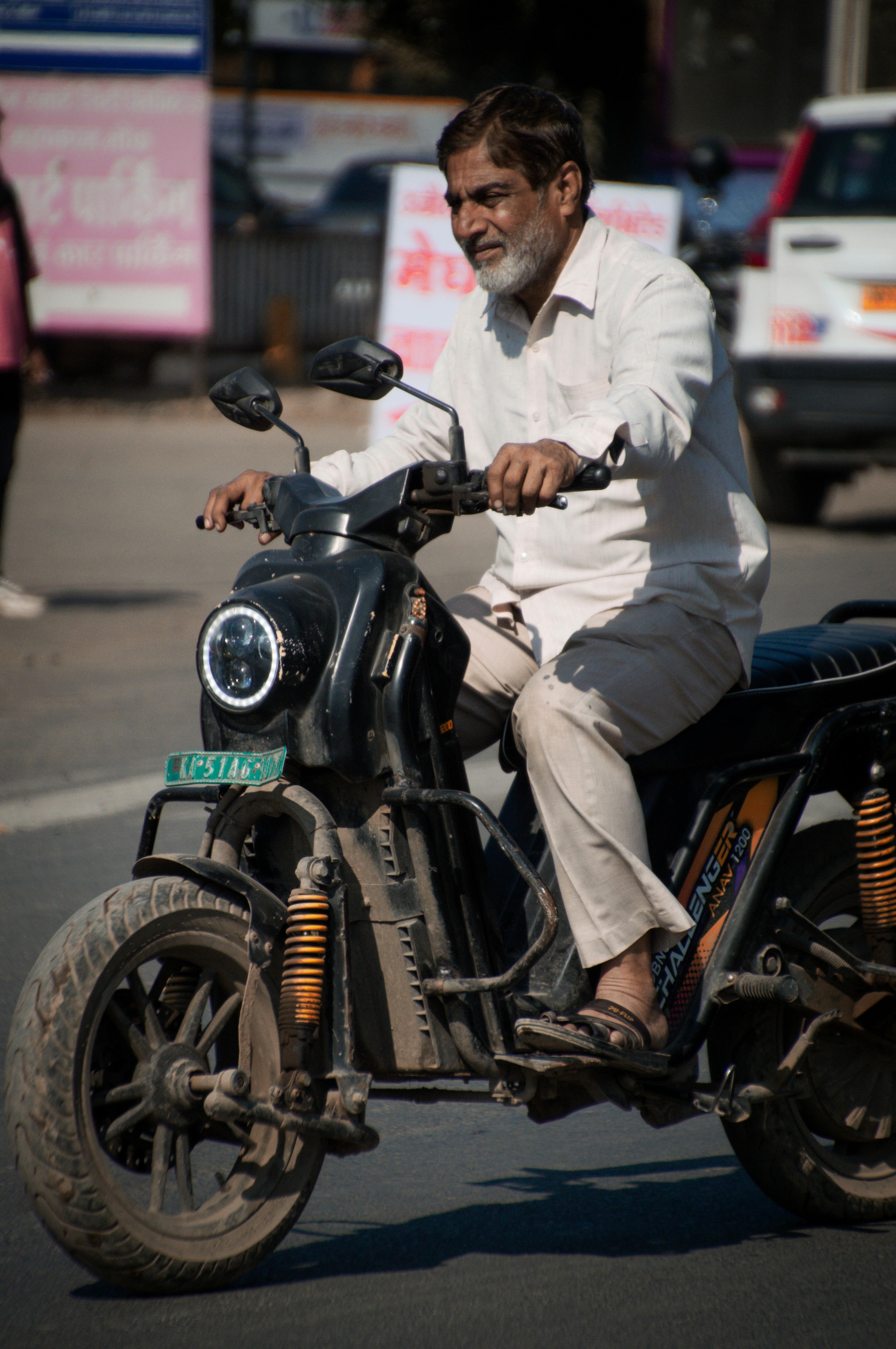 An older man rides a black electric scooter.
