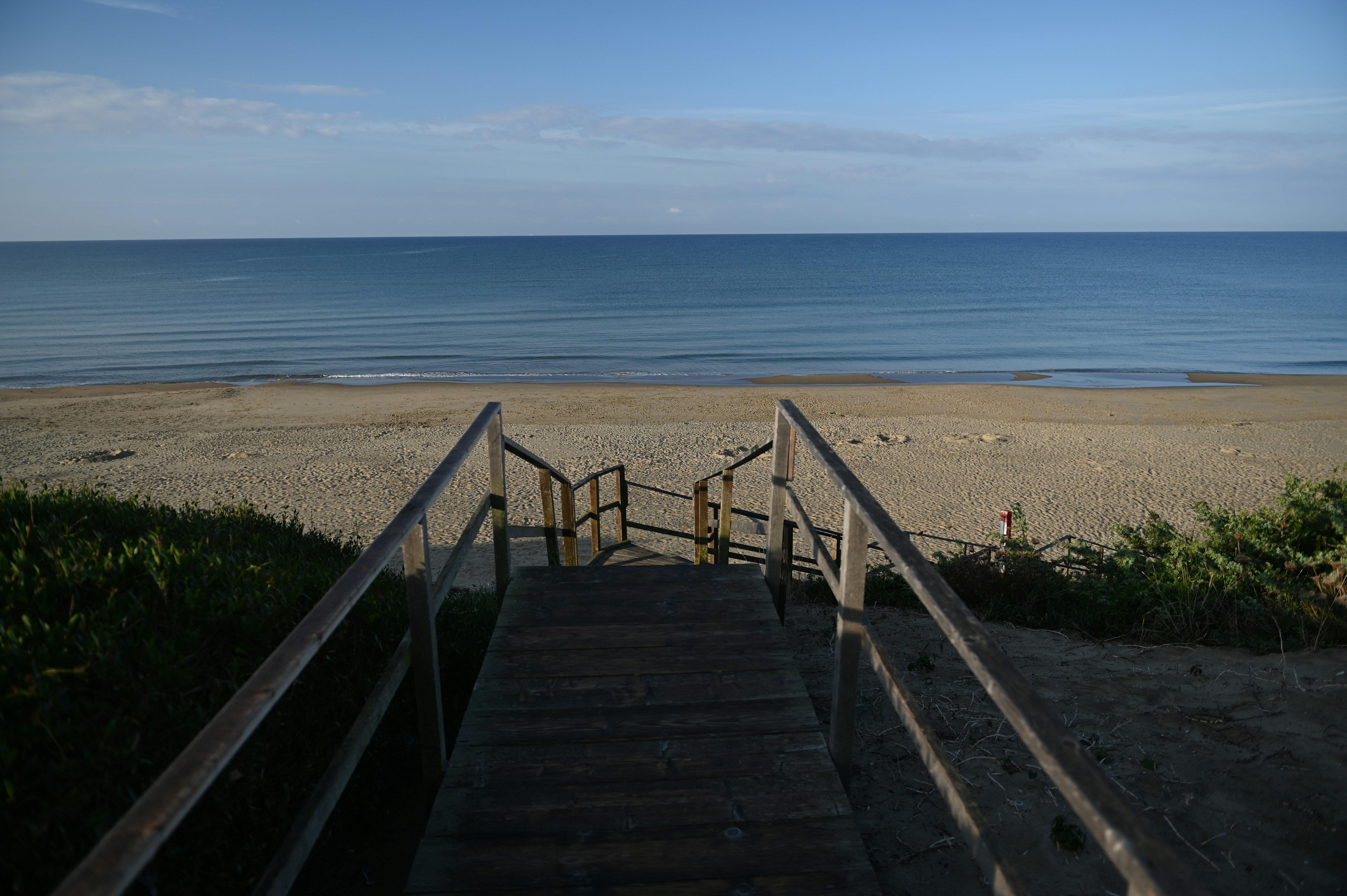Scale di legno che portano a una spiaggia sabbiosa e all'oceano.