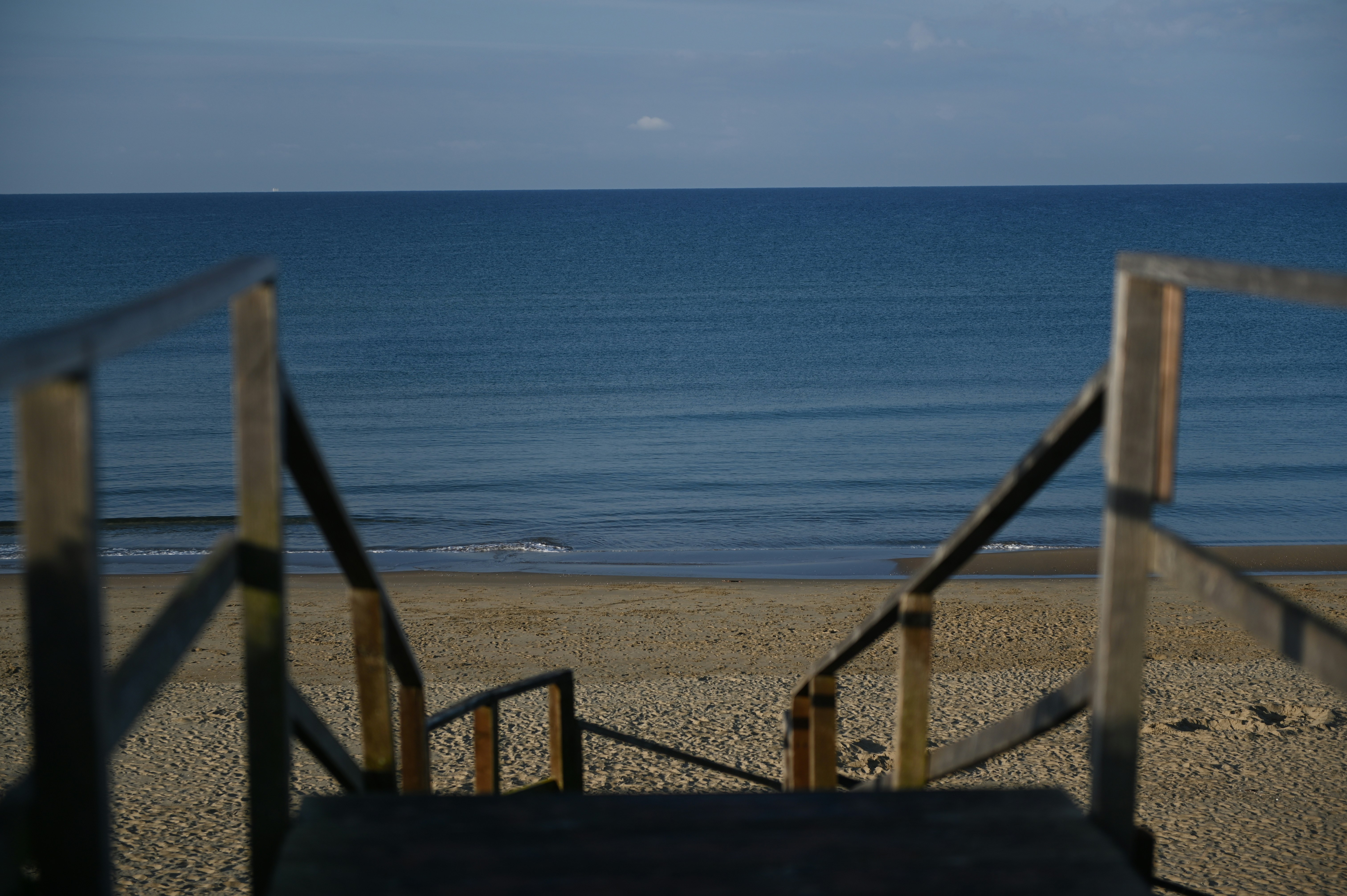 Scale di legno che portano a una spiaggia sabbiosa e all'oceano