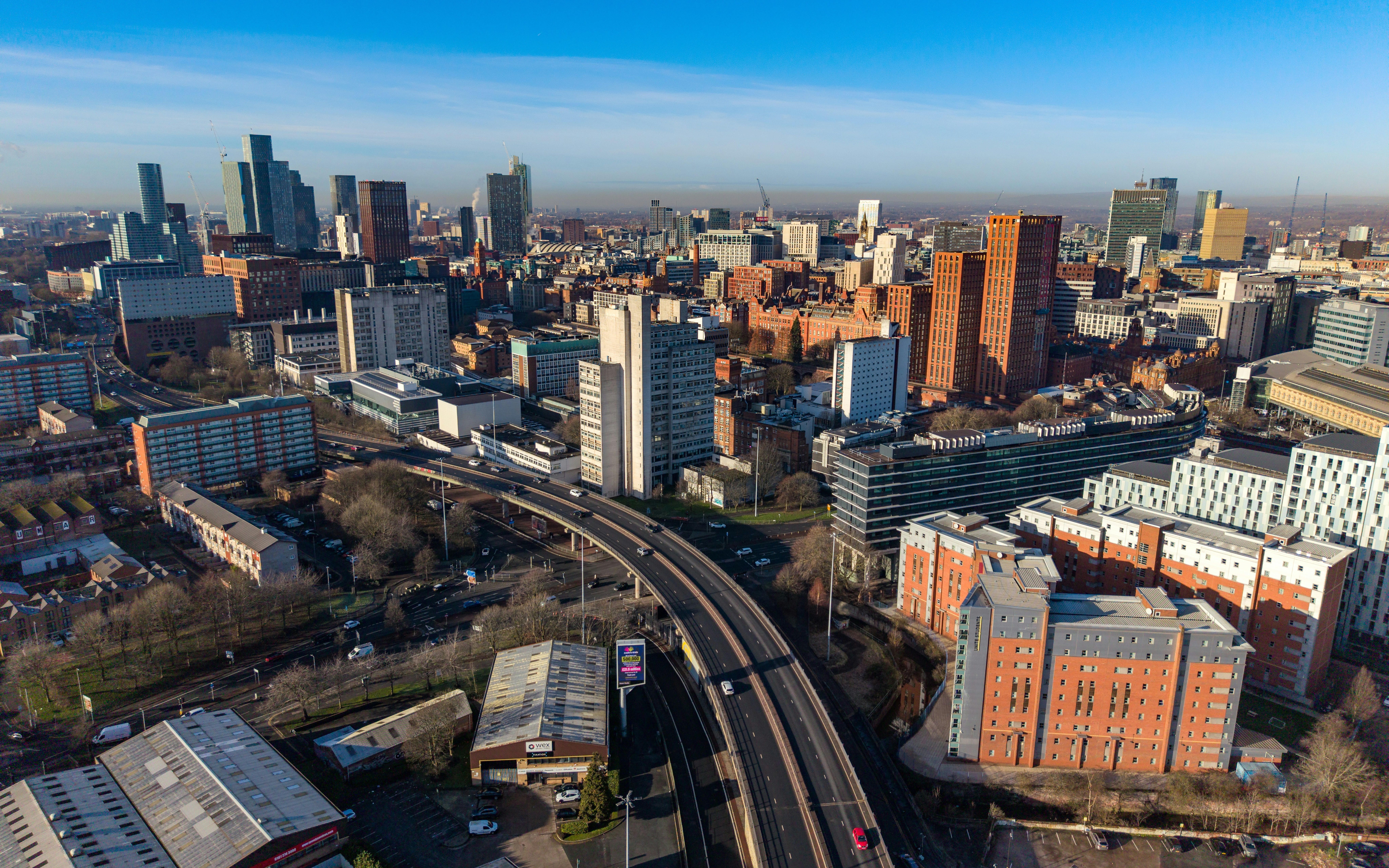 Luftaufnahme einer weitläufigen Stadtlandschaft mit Autobahnen und Gebäuden.