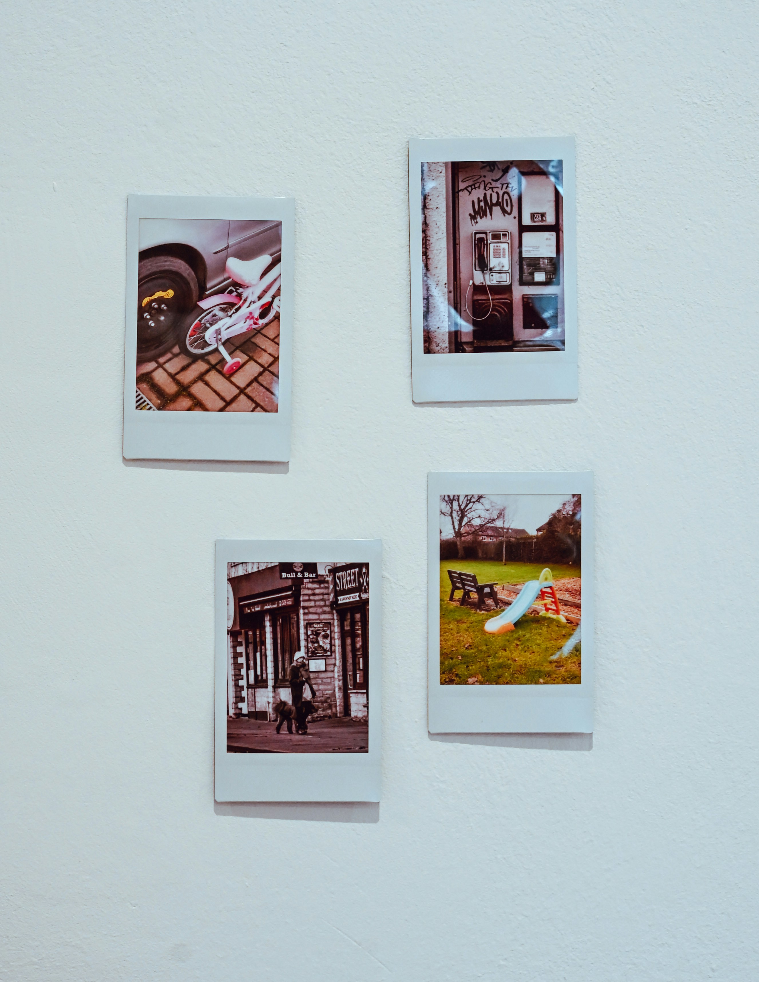 Quatro fotos instantâneas exibidas em uma parede branca.