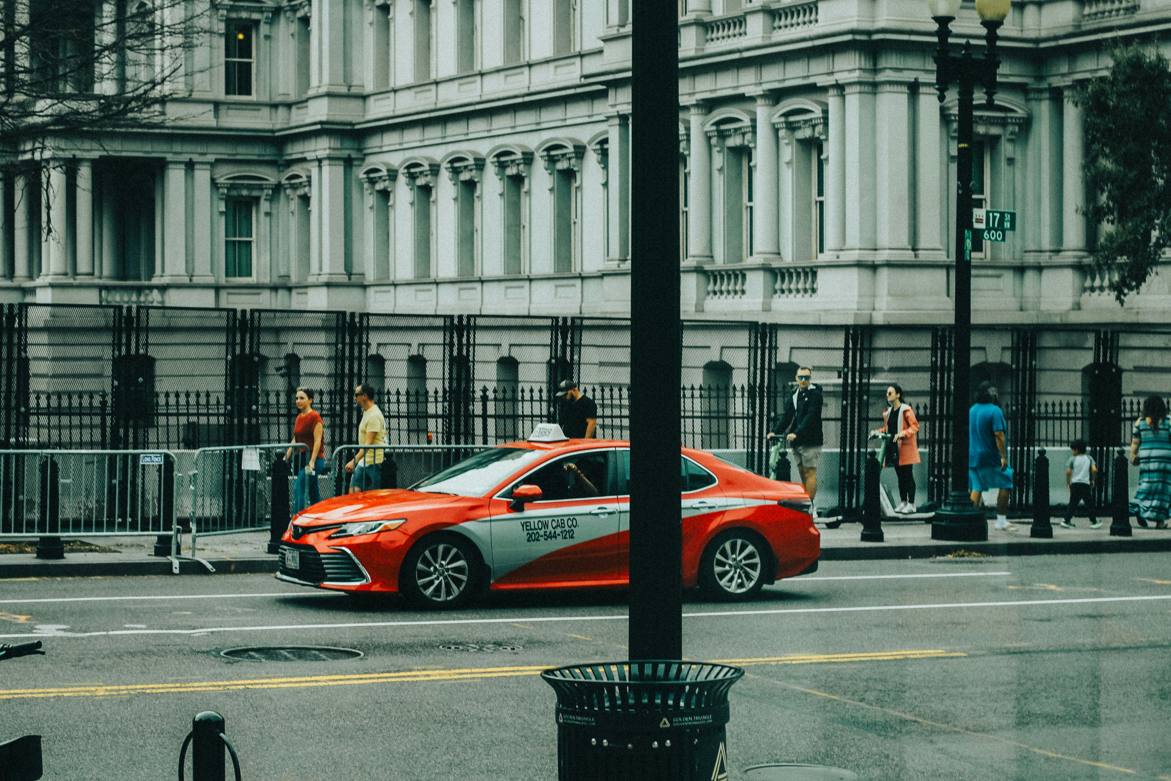 Red and white taxi drives past a grand building.