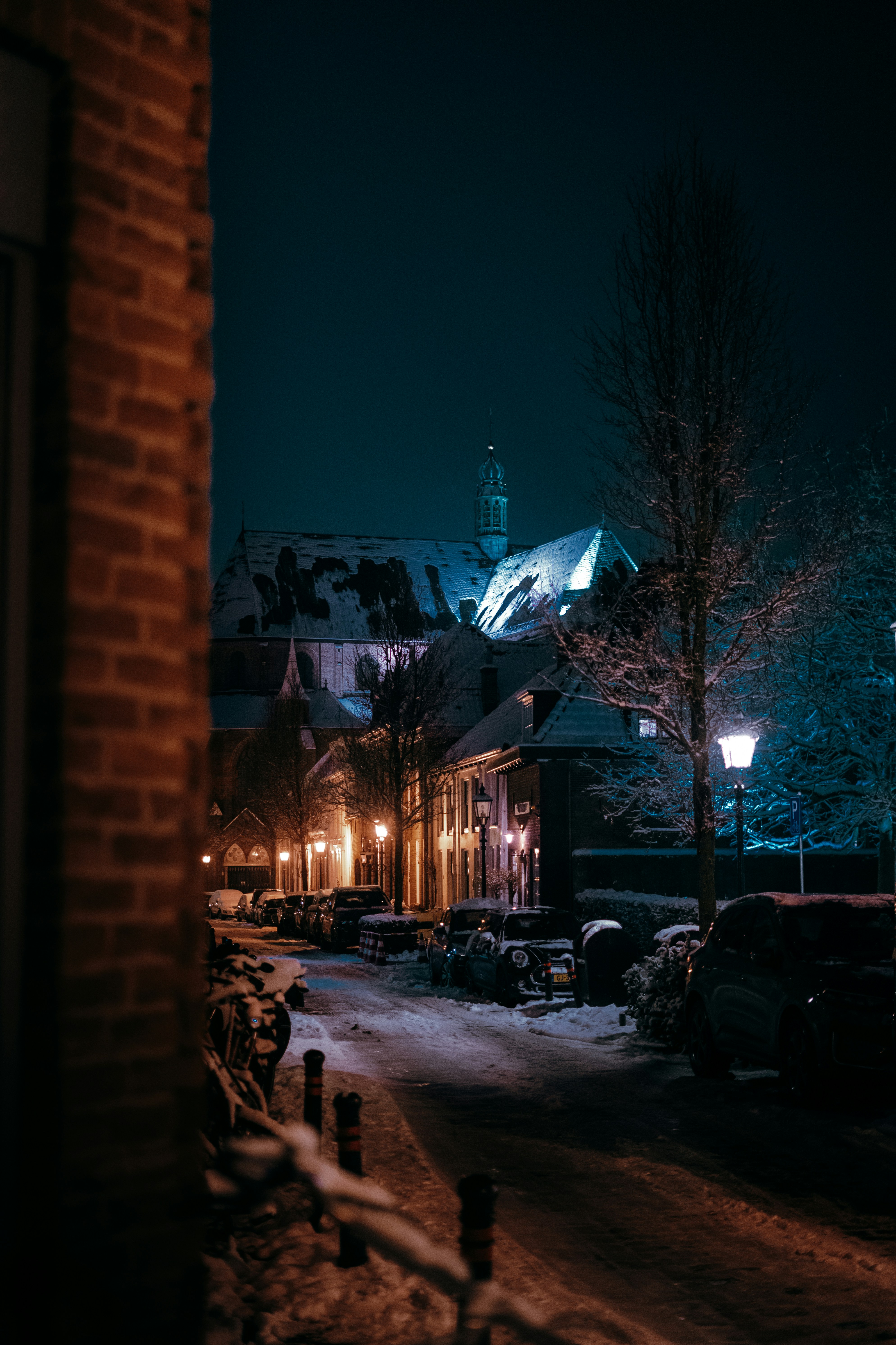 Snowy street with illuminated buildings at night.
