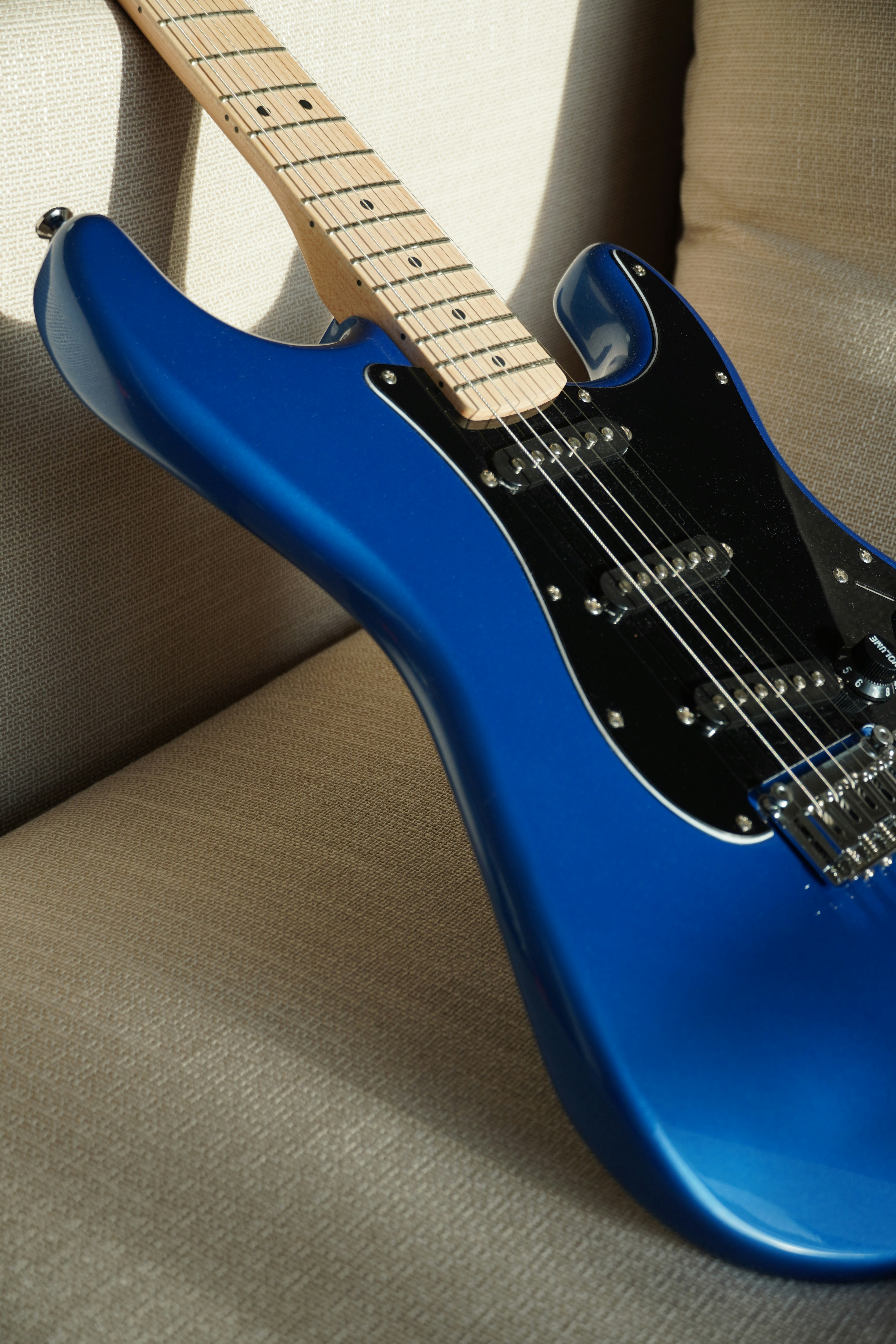 Eine glänzende blaue E-Gitarre ruht auf einer strukturierten Oberfläche.