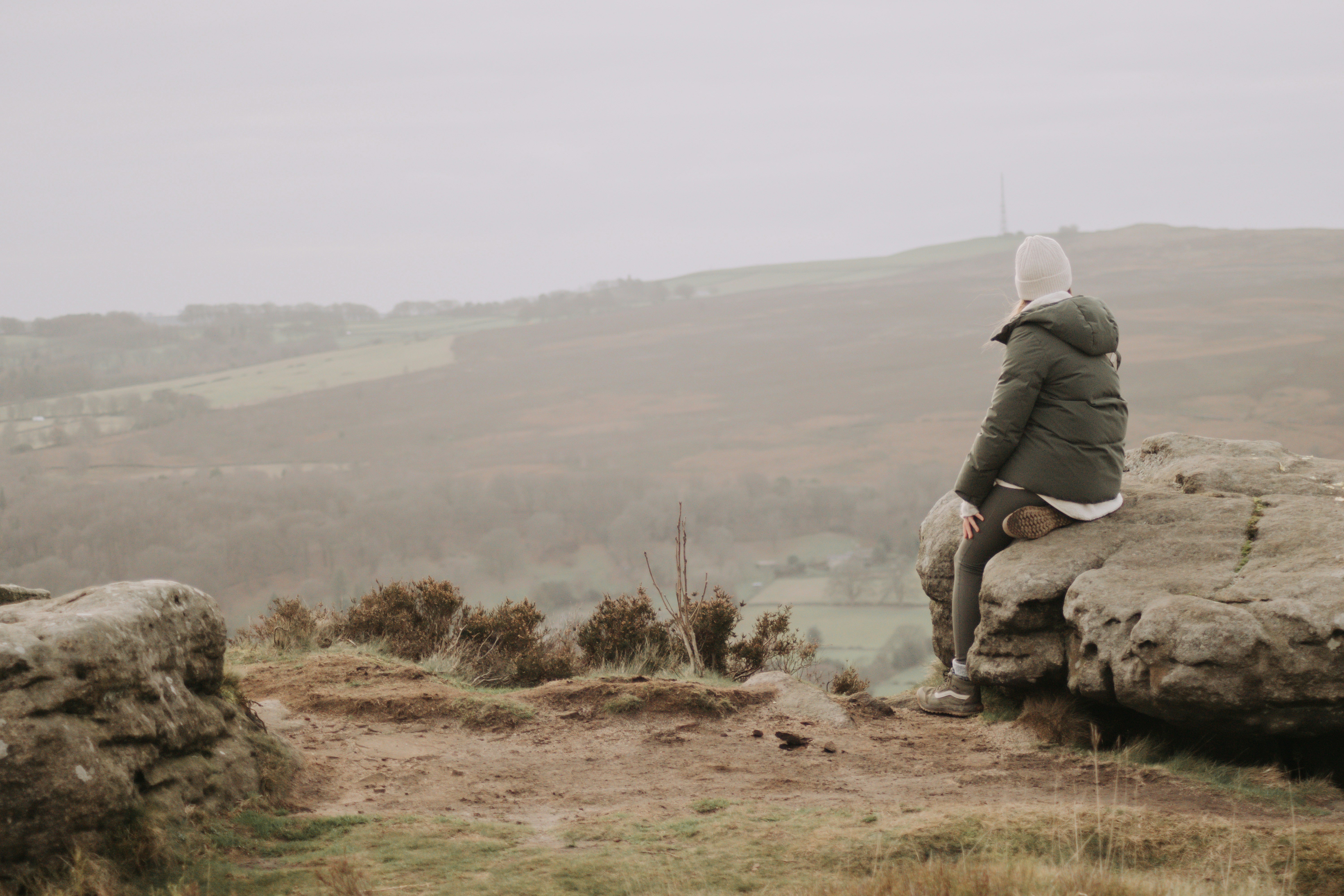 Person sitting on a rock overlooking misty hills