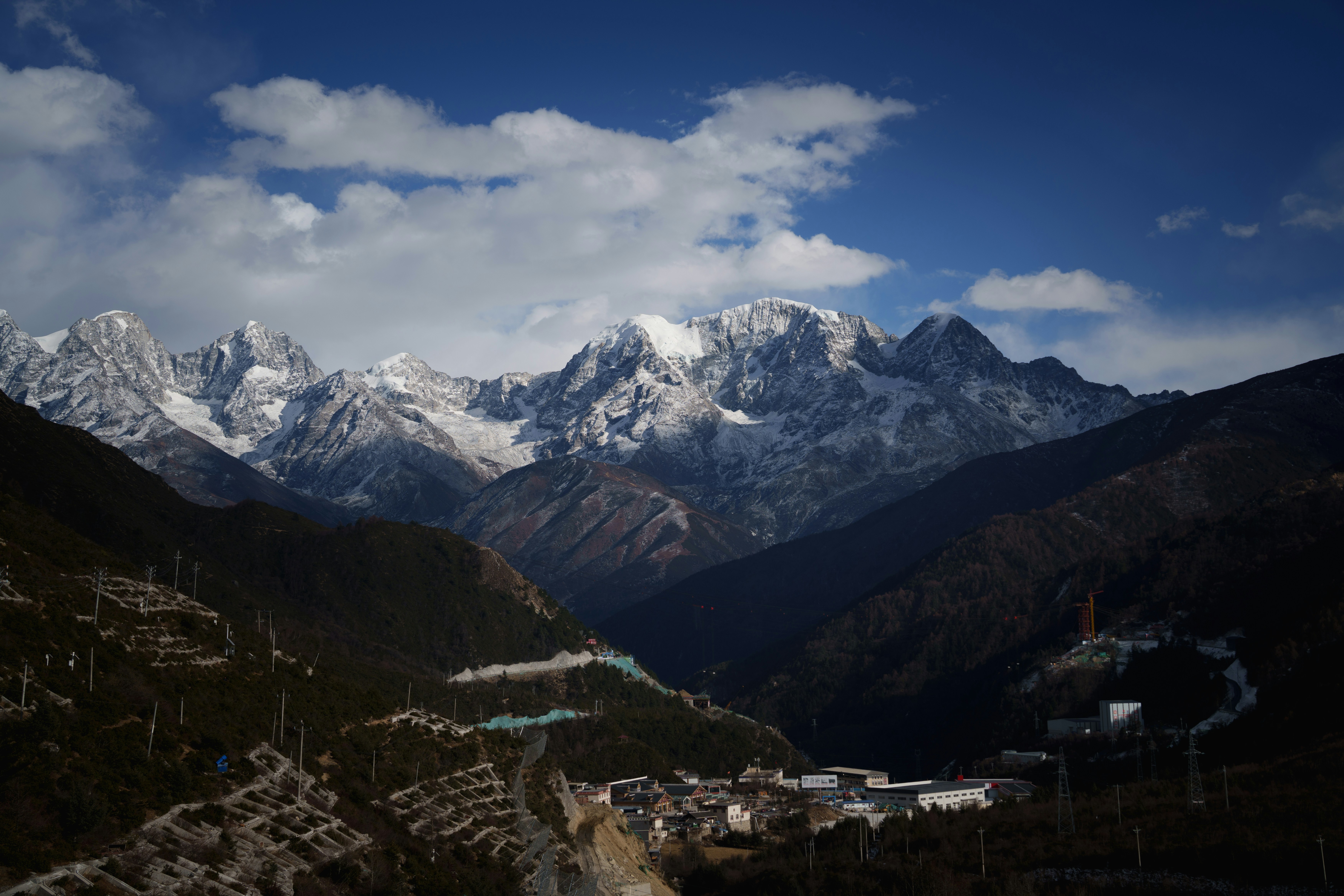 Snow-capped mountains under a cloudy blue sky.