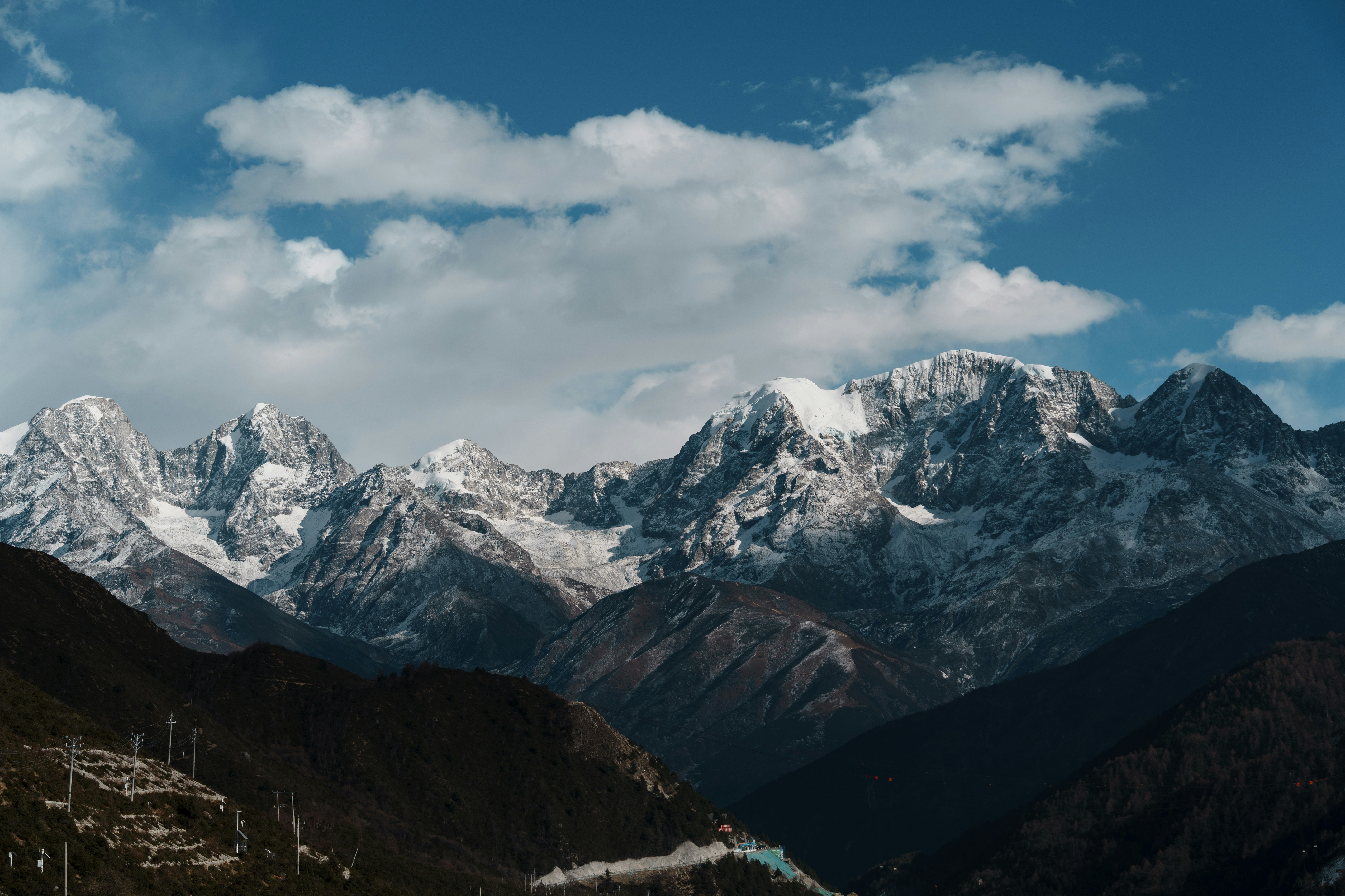 Snow-capped mountains under a cloudy blue sky