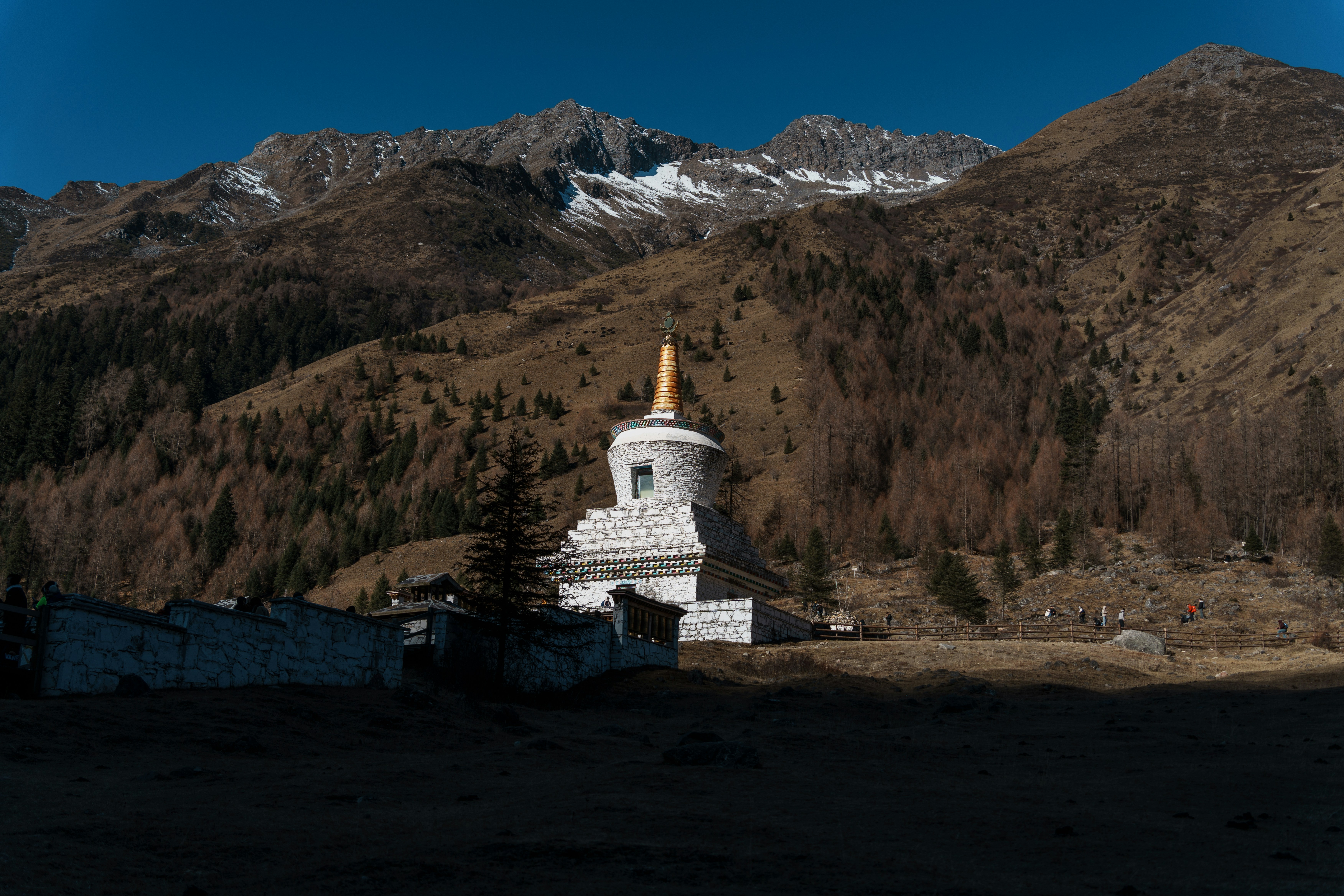 A white stupa stands before a mountain range.