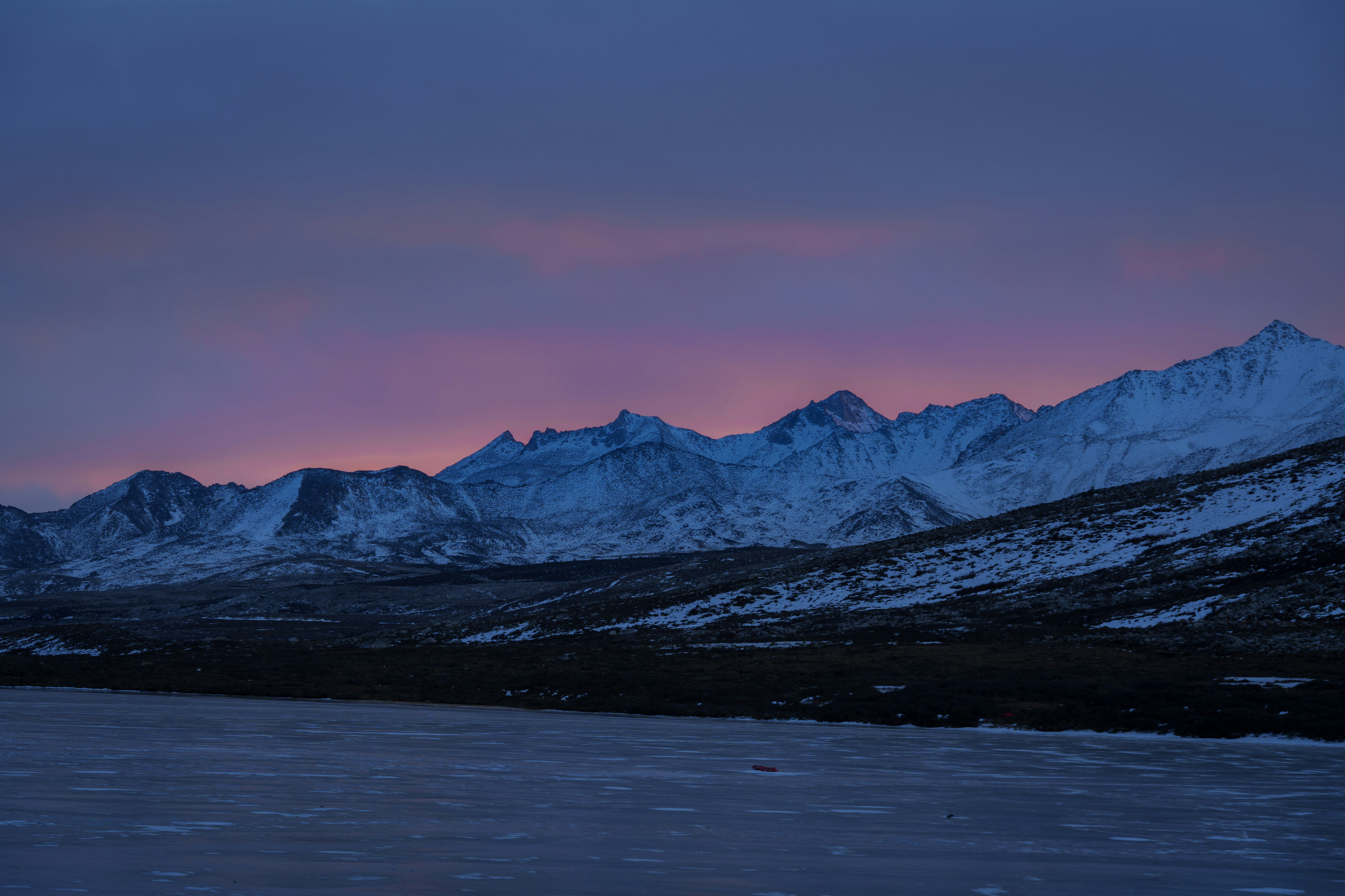 Snowy mountain range under a pink and purple sky
