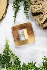 A small jar of cream on a wooden square.