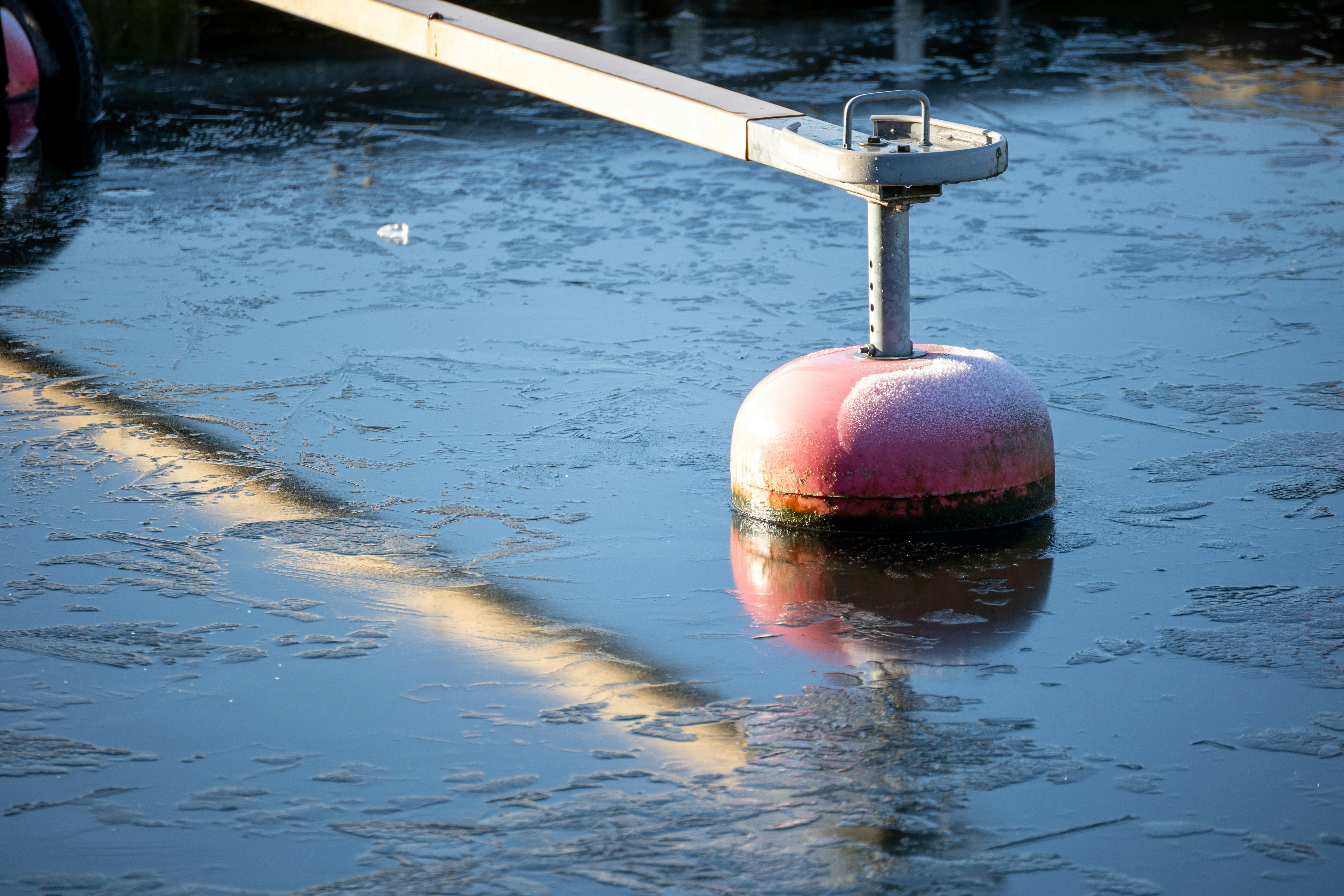 Red buoy floating on icy water surface