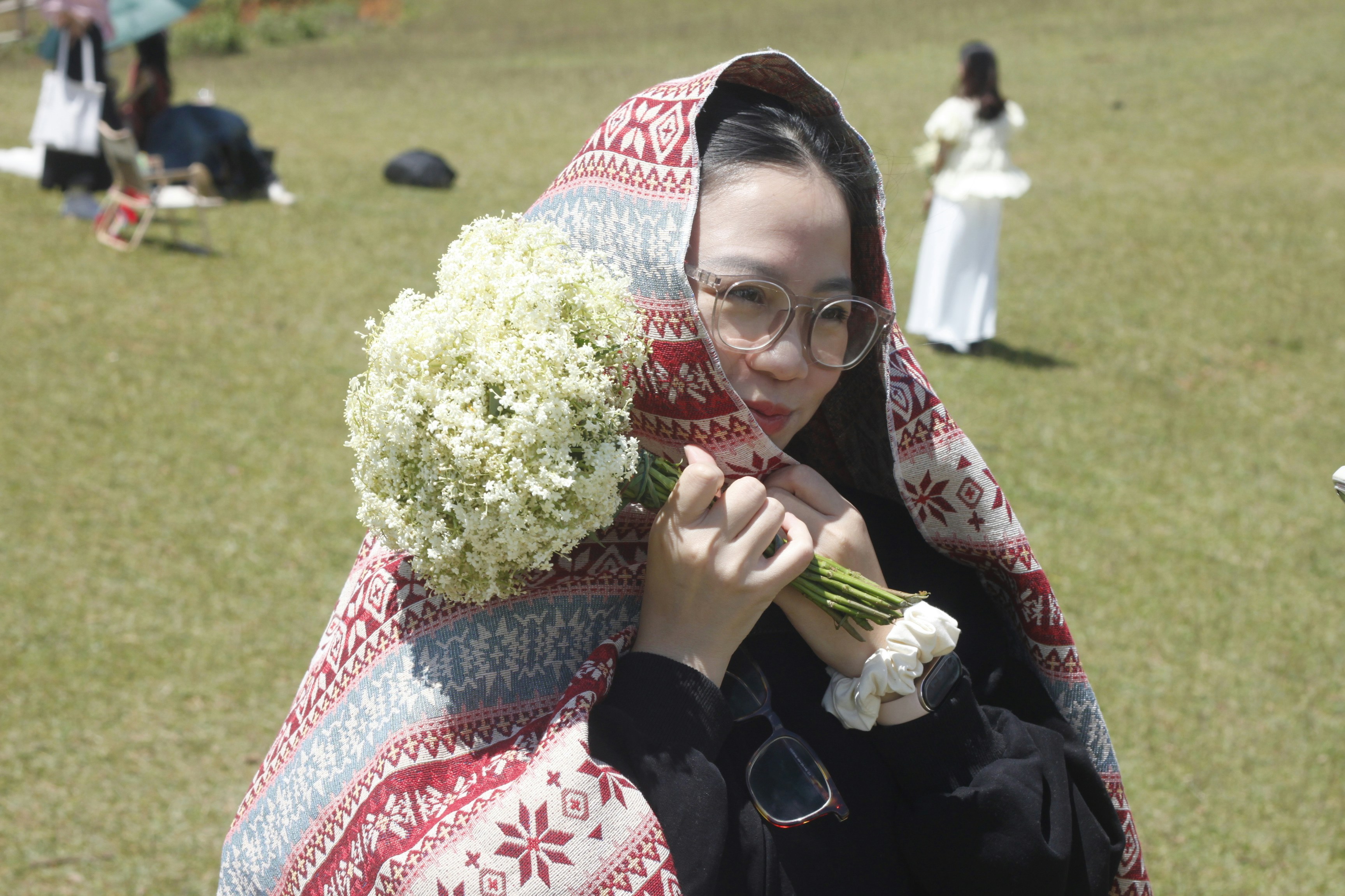 Woman wrapped in patterned blanket holding flowers