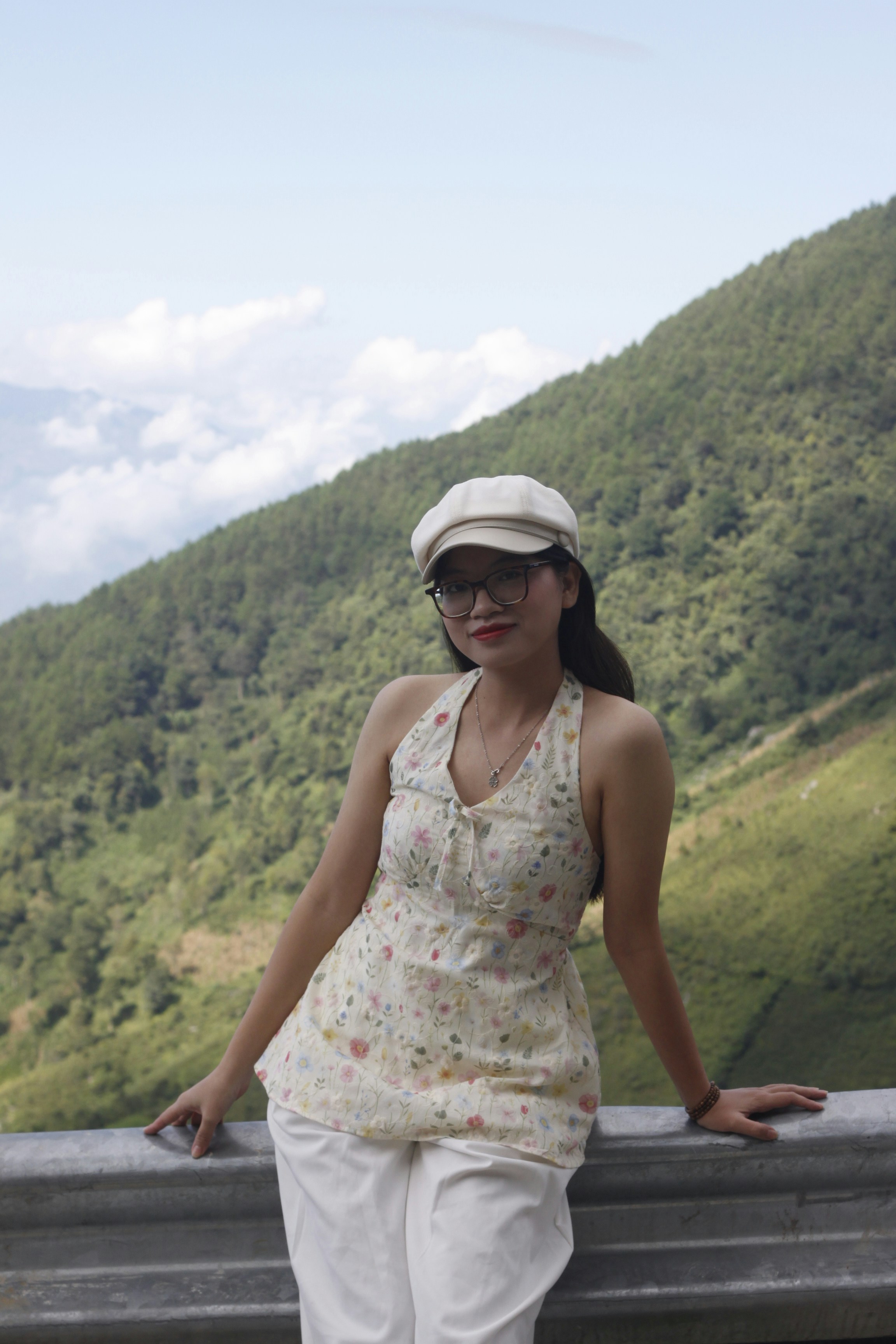 Woman in hat and glasses poses on mountain road