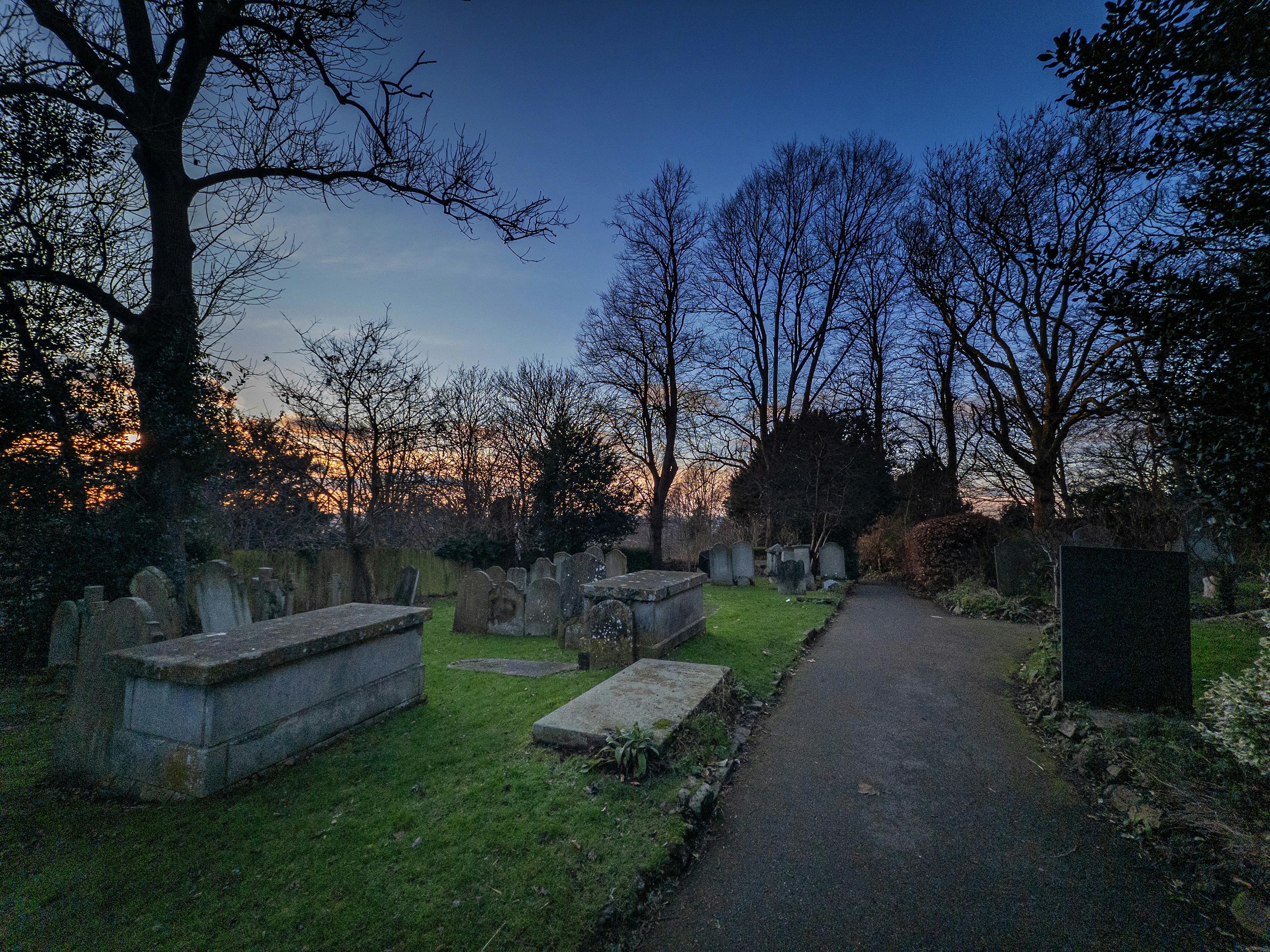 A pathway through a cemetery at dusk