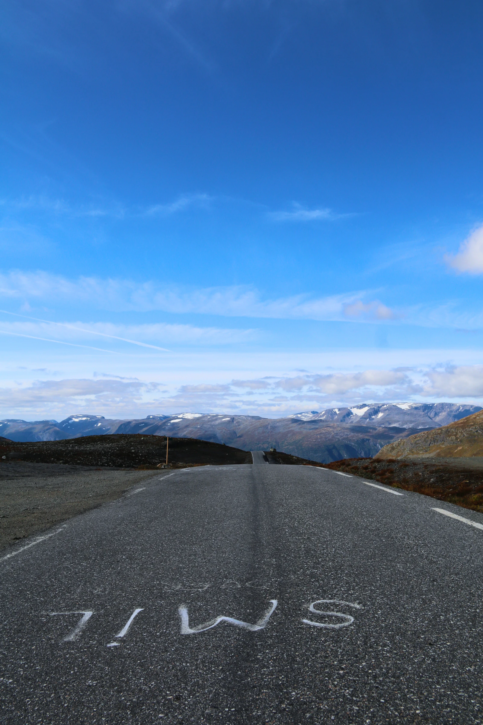 A road leads toward snow-capped mountains in Norway