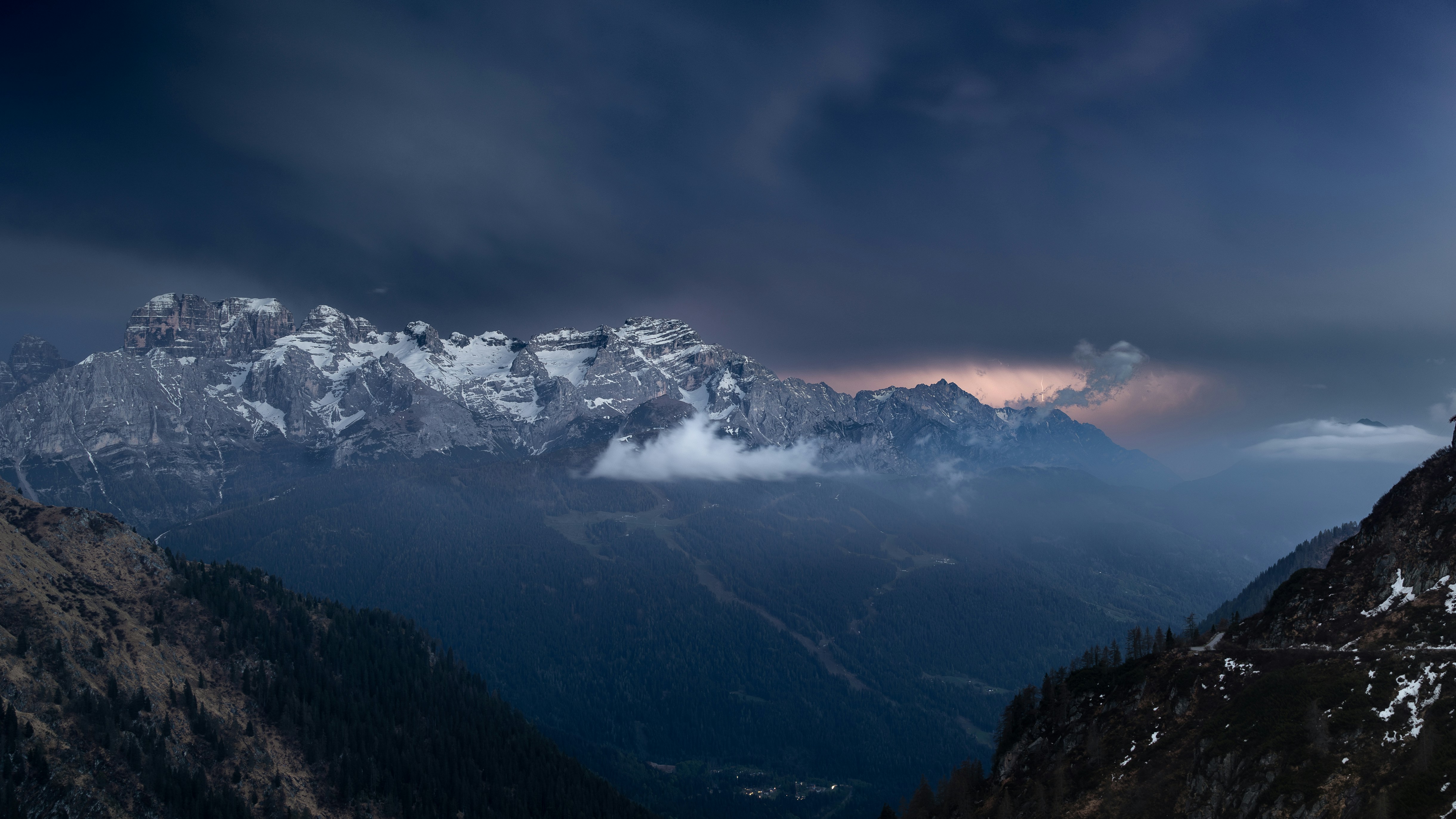 Snow-capped mountains under a stormy, dark sky.