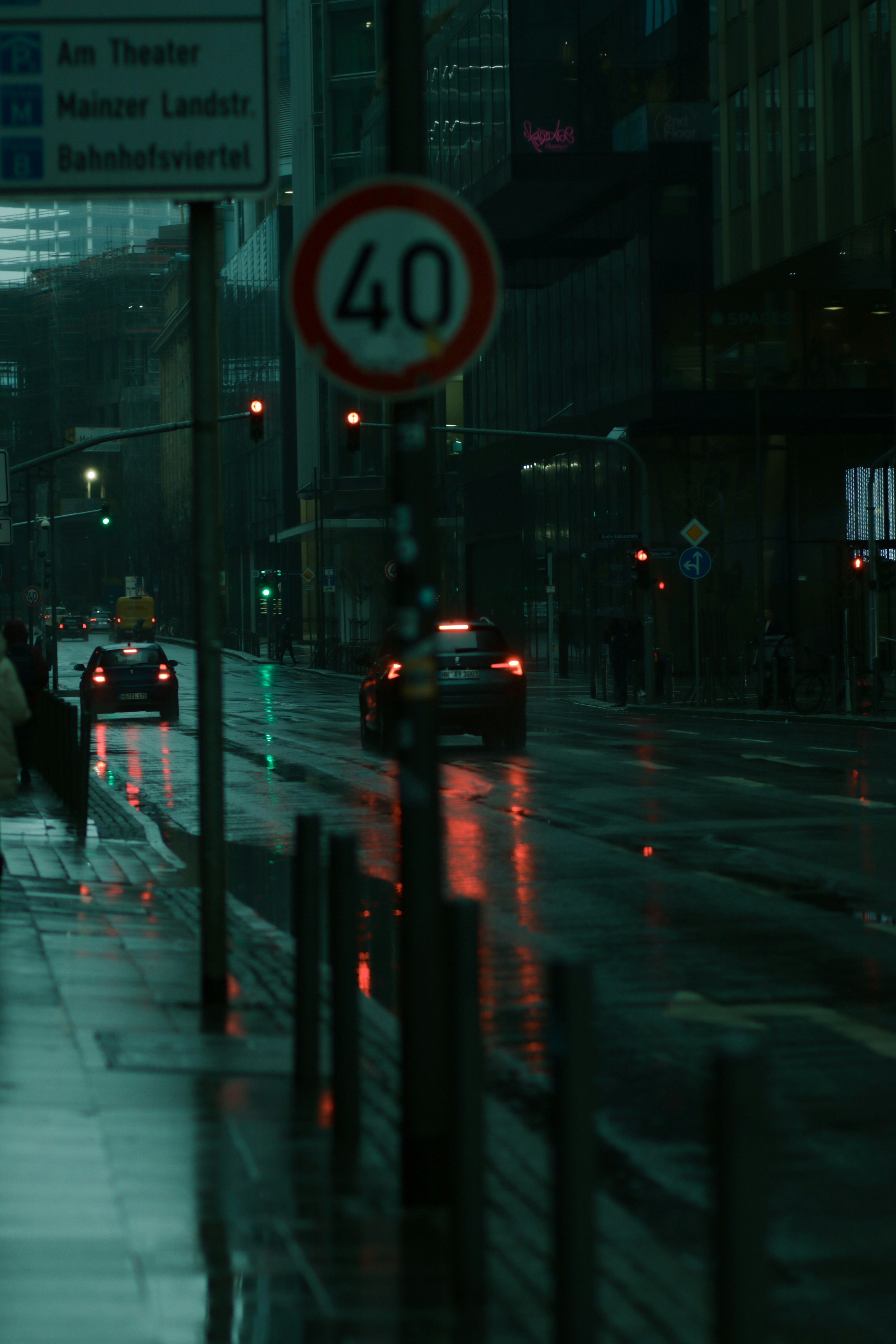 Cars driving on a wet city street at night.