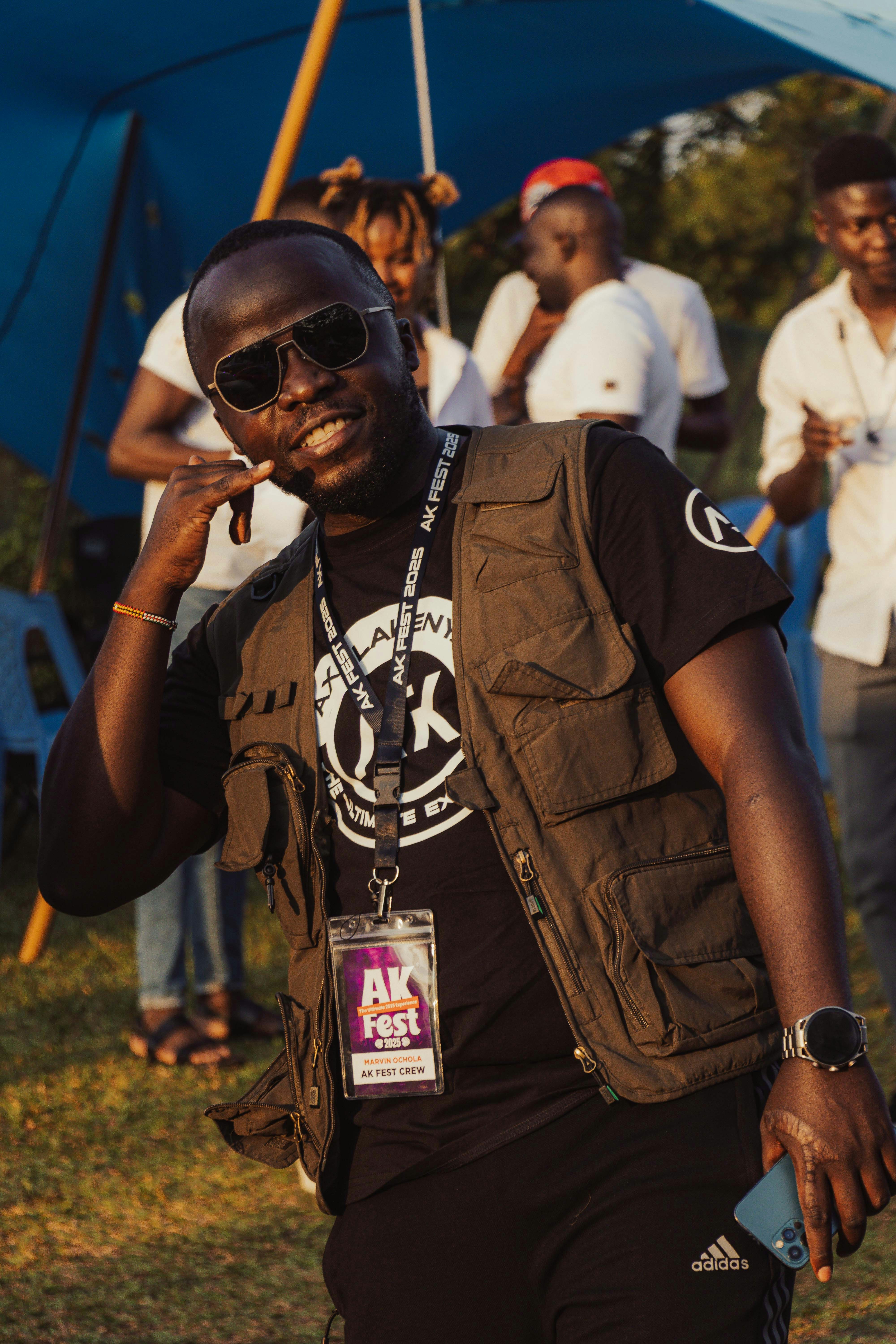 Man in sunglasses and vest makes a gesture.