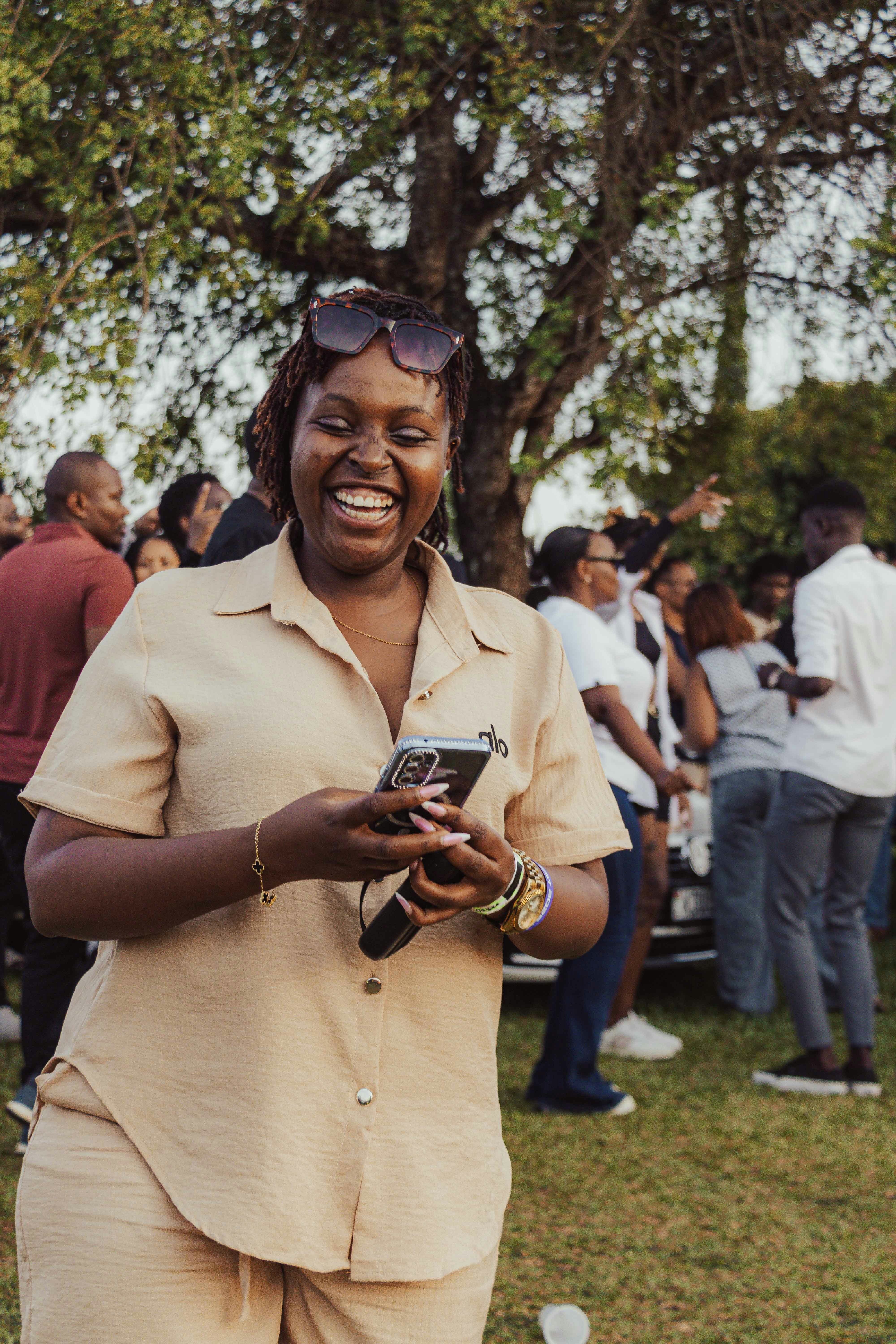 A smiling woman holding a smartphone outdoors