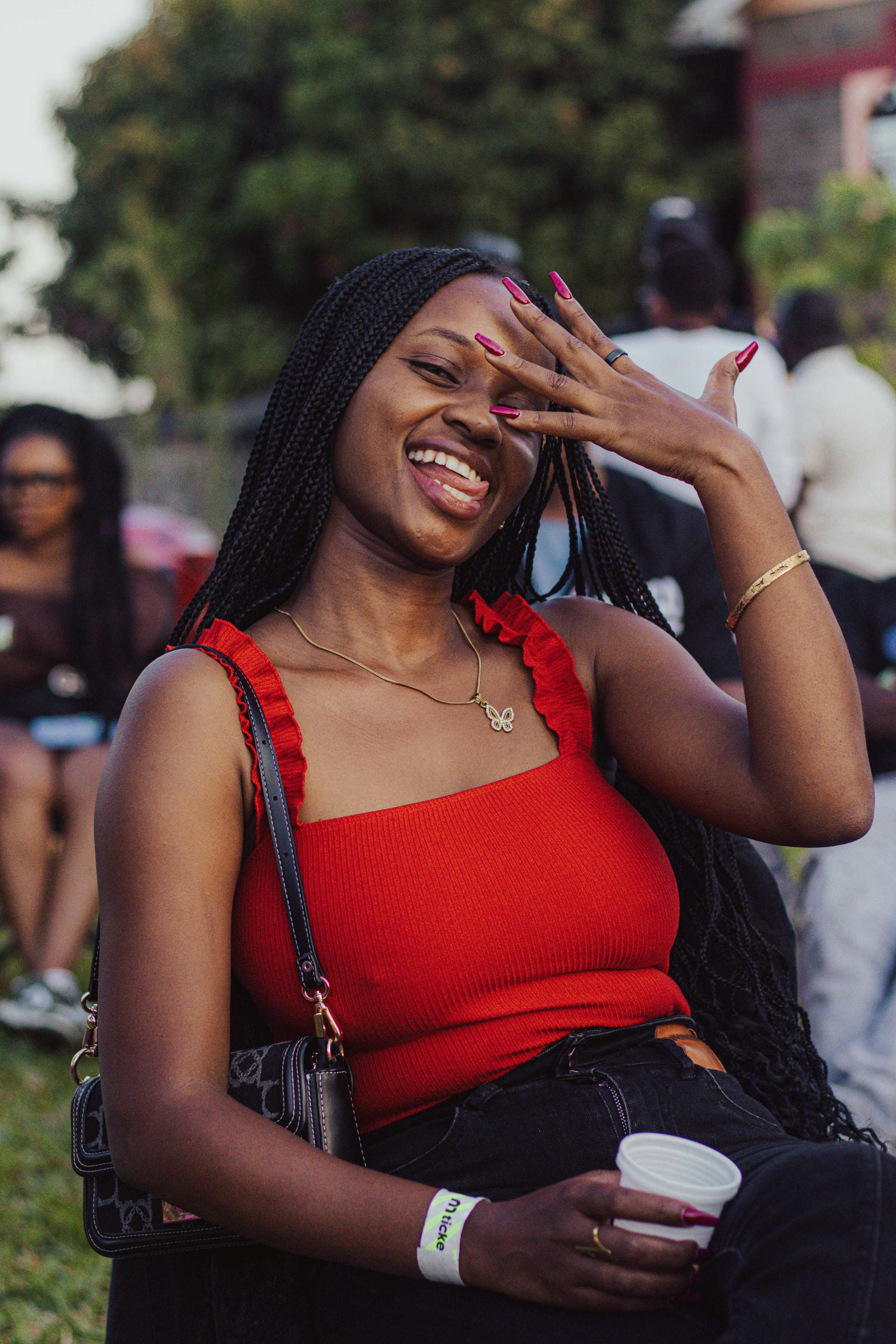 A woman in a red top laughing outdoors