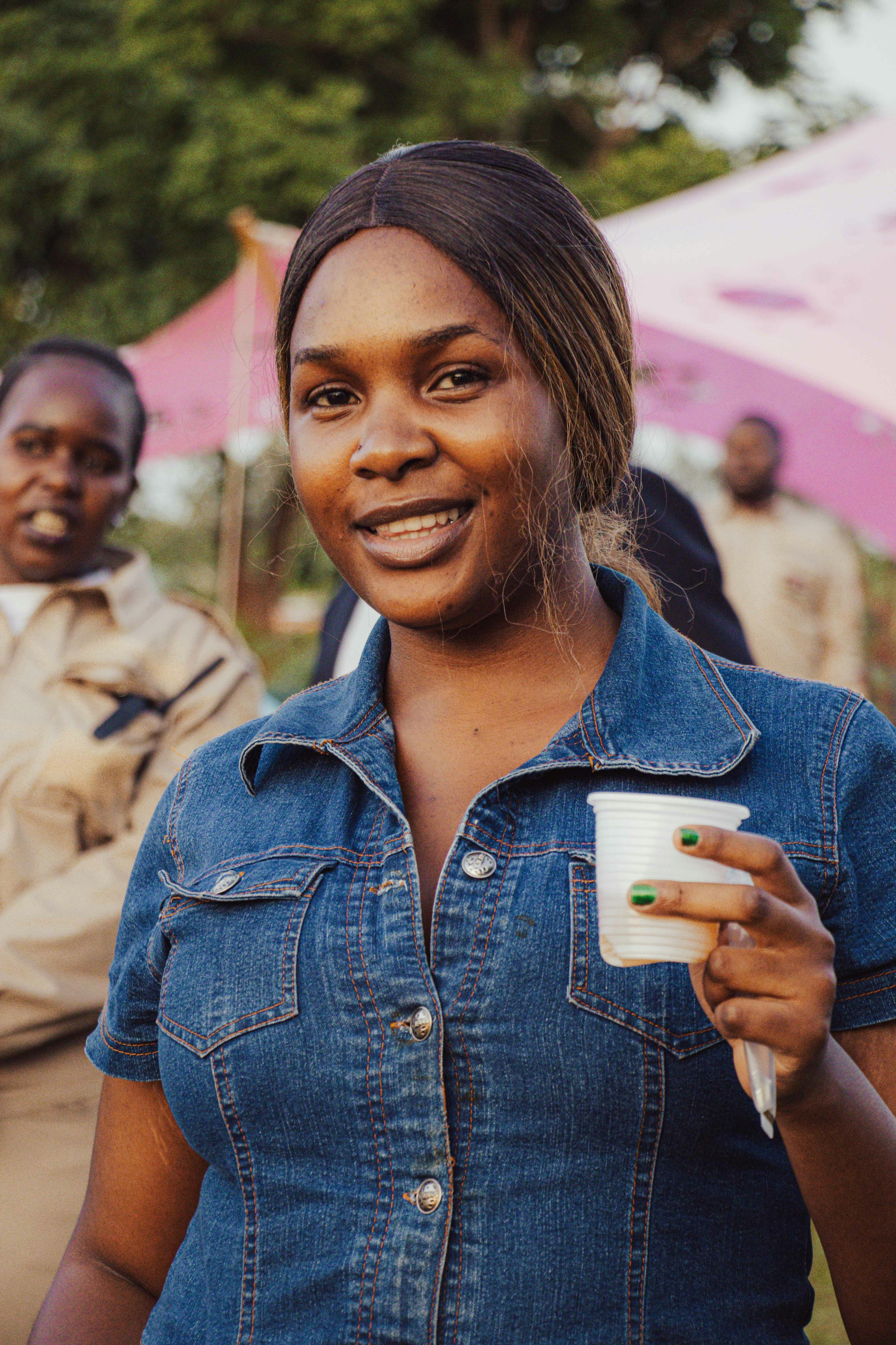 A woman in a denim shirt holds a cup