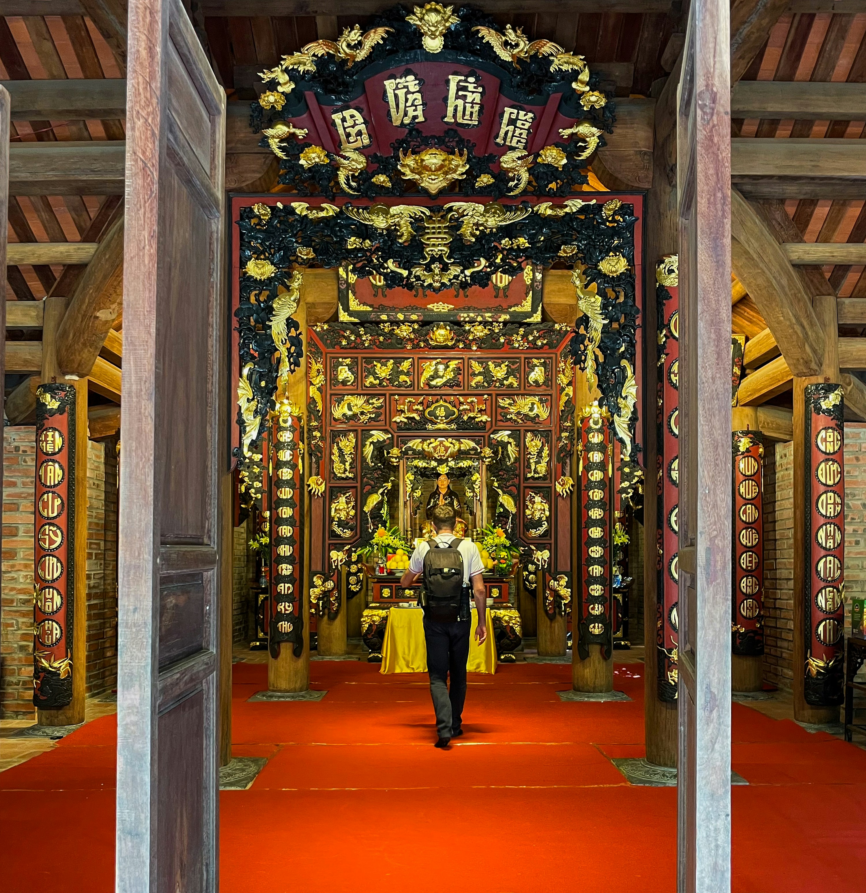 Person attraversa l'ingresso ornato del tempio con tappeto rosso.