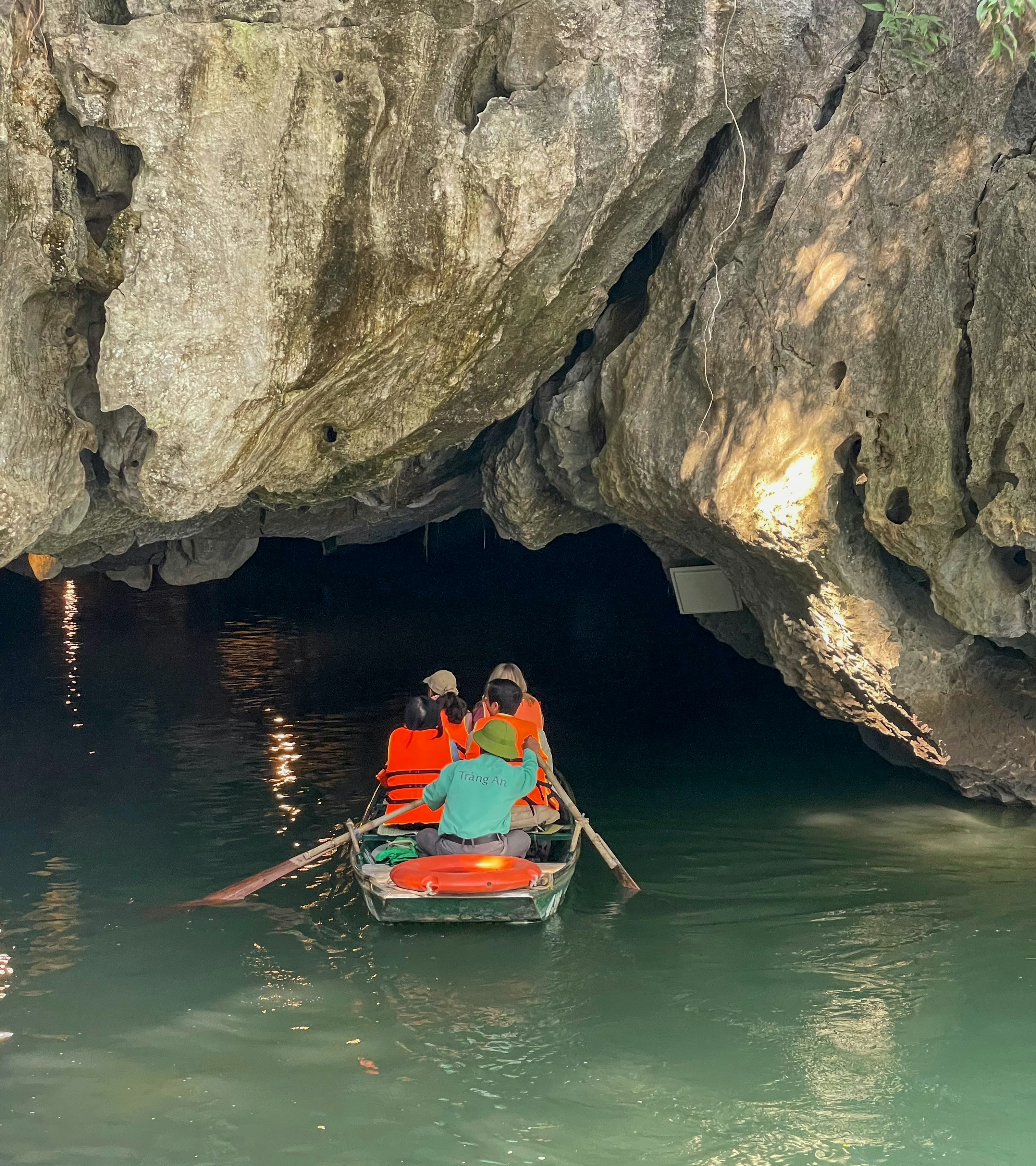 Persone che remano in barca dentro un ingresso buio di una grotta.