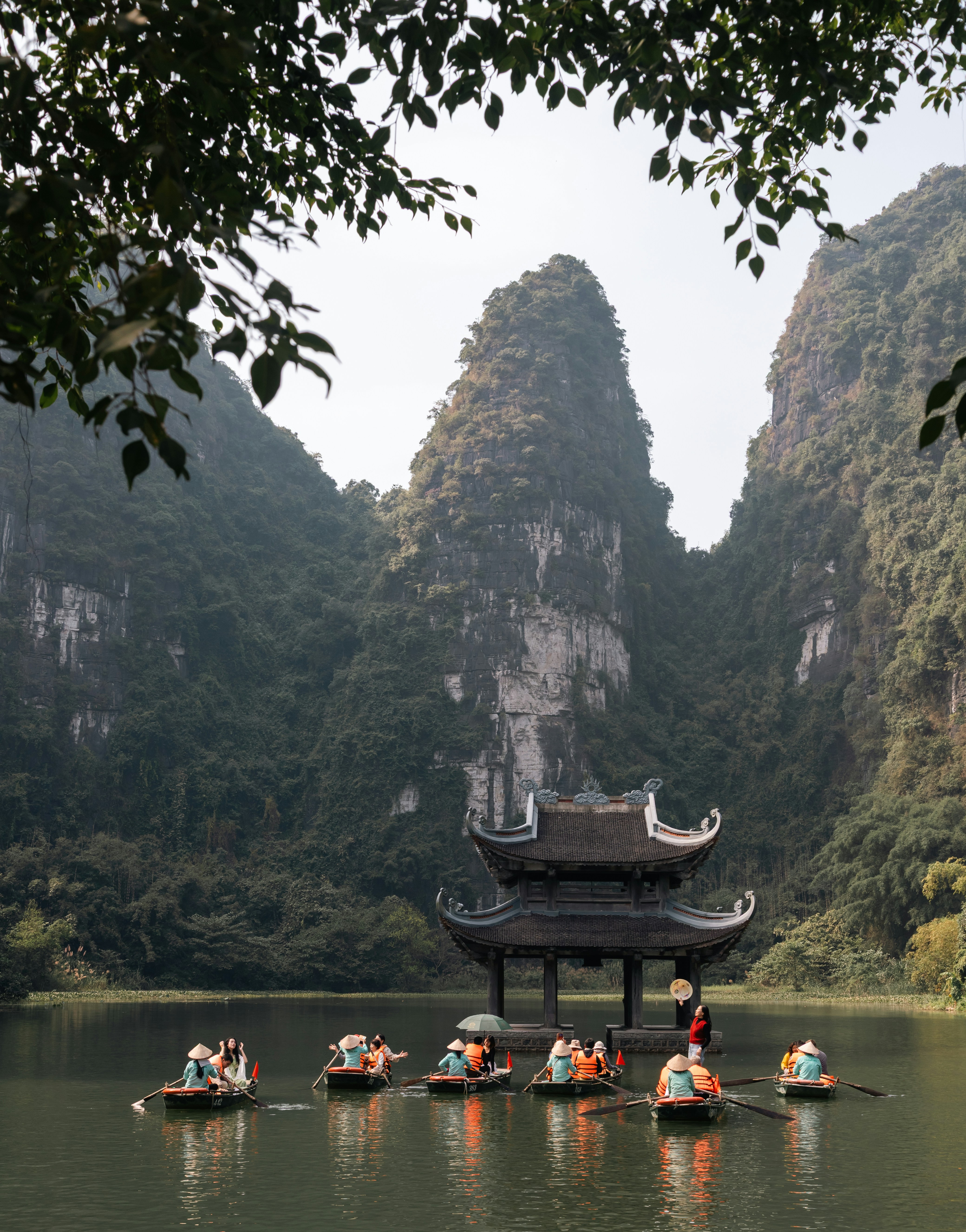 Le barche galleggiano sull'acqua vicino a un tempio e alle montagne.