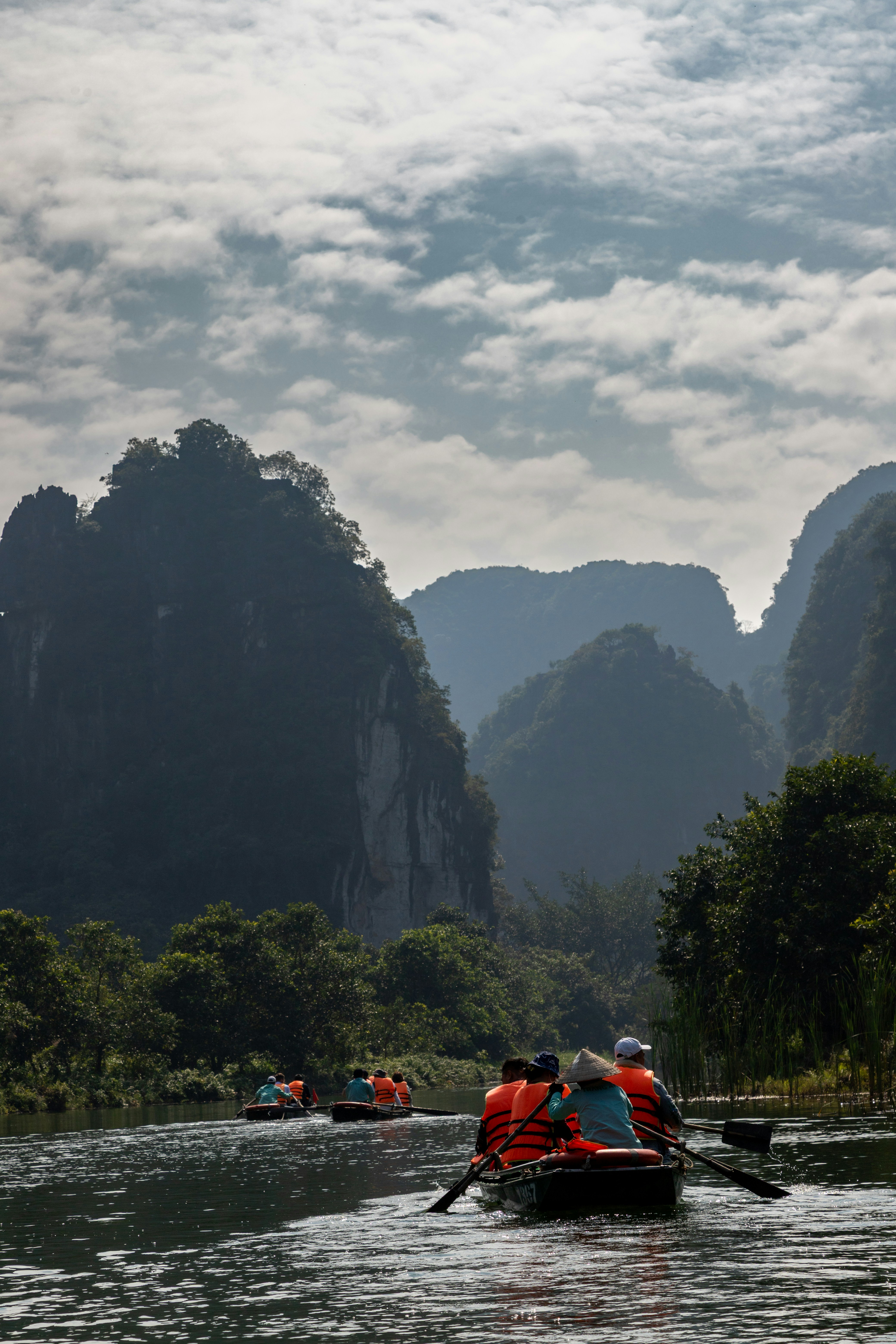 Le barche scivolano su un fiume panoramico circondato da montagne carstiche.