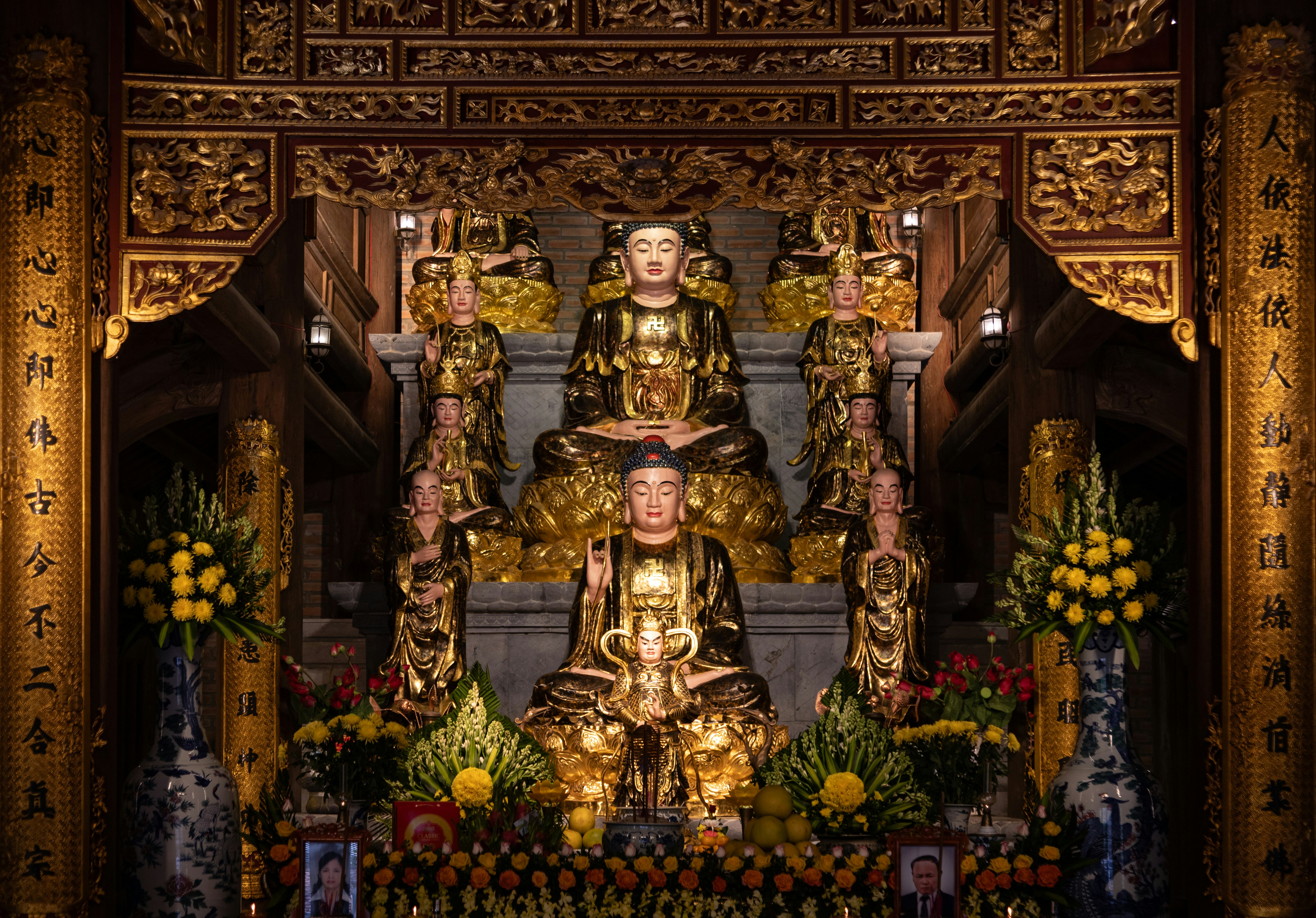 Ornate altar with golden buddhist statues and floral arrangements.