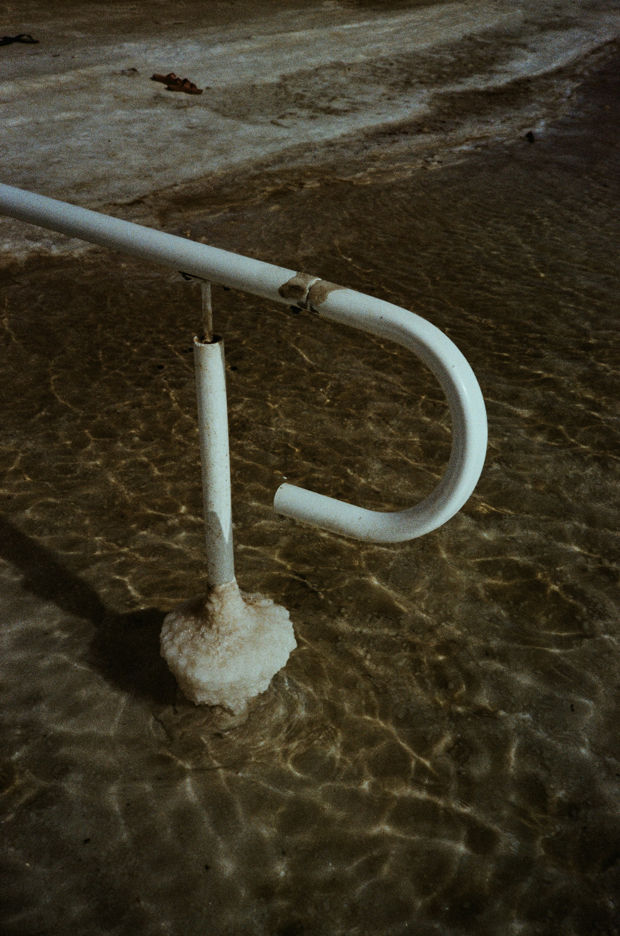 White handrail partially submerged in shallow water.