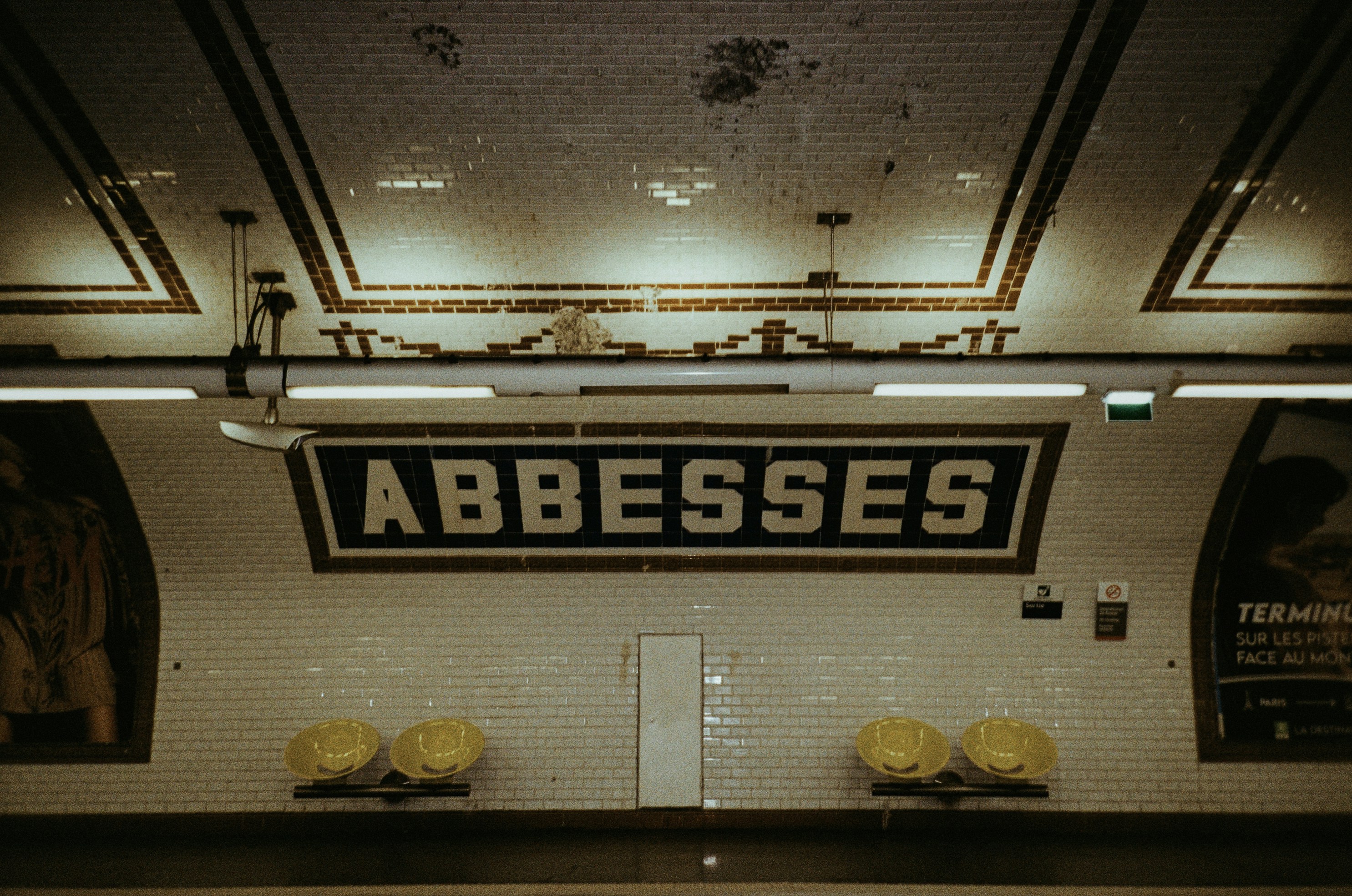 Abbesses metro station sign with tiled walls.